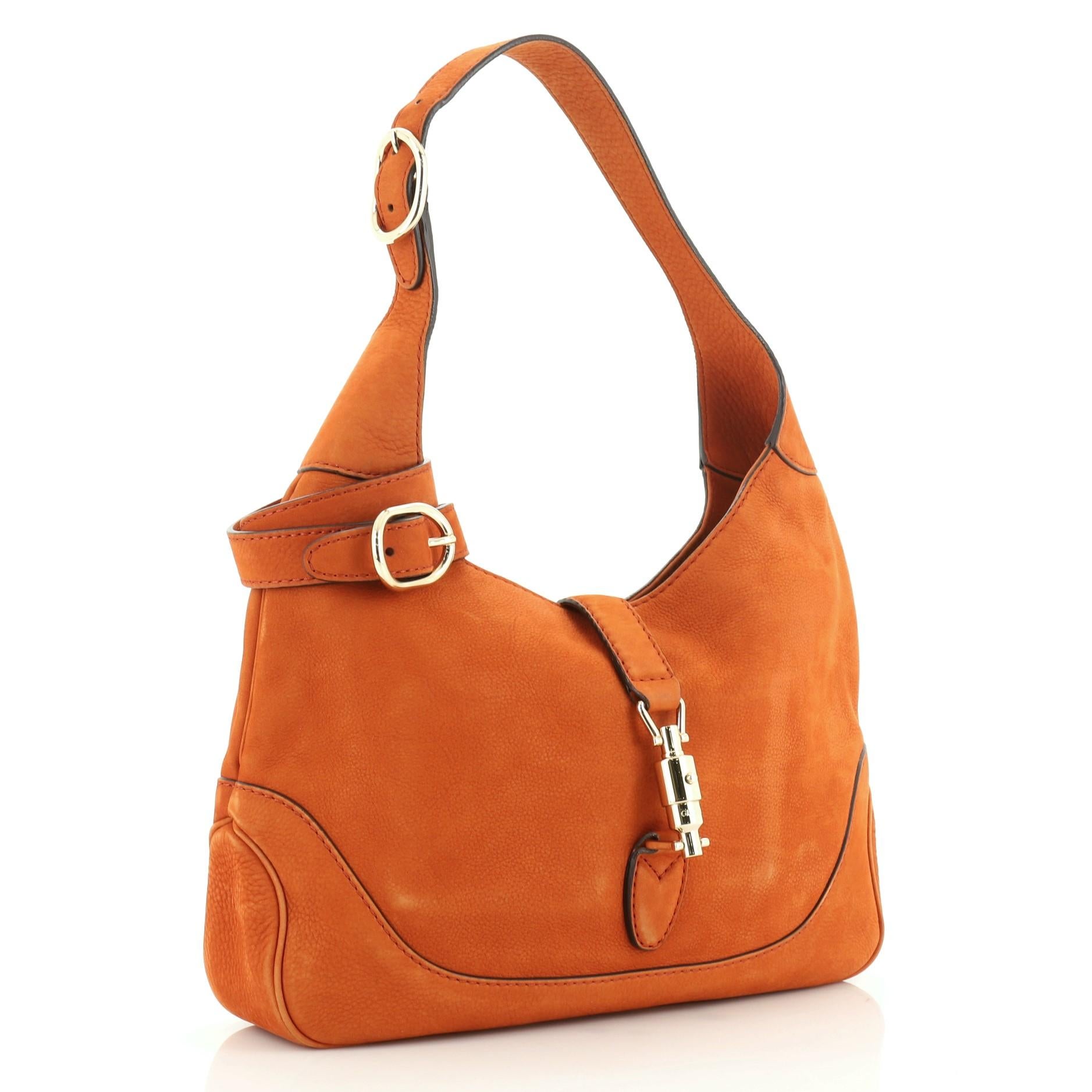 This Gucci Jackie Original Shoulder Bag Nubuck Medium, crafted from orange nubuck, features an adjustable shoulder strap and gold-tone hardware. Its piston lock closure opens to a neutral fabric interior with zip and slip pockets. 

Estimated Retail
