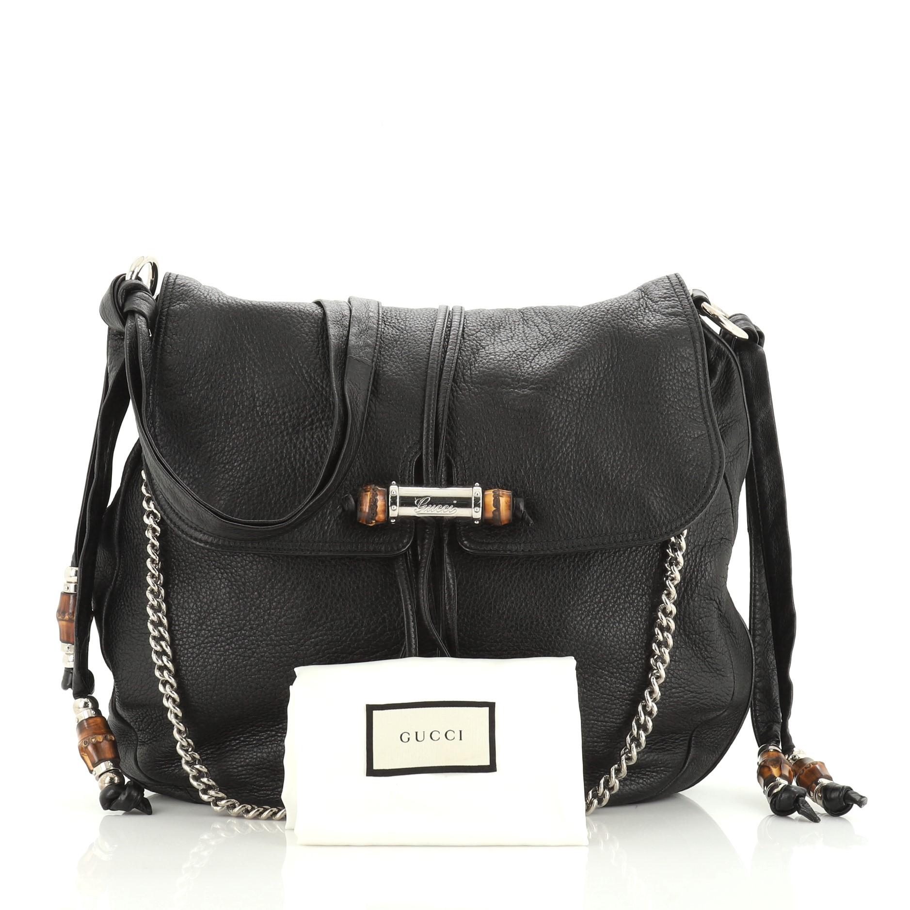 This Gucci Jungle Messenger Bag Leather Large, crafted from black leather, features gunmetal and bamboo-embellished leather crossbody strap with an adjustable knot, detachable metal chain strap, a fold-over flap with gunmetal-embellished tassels to