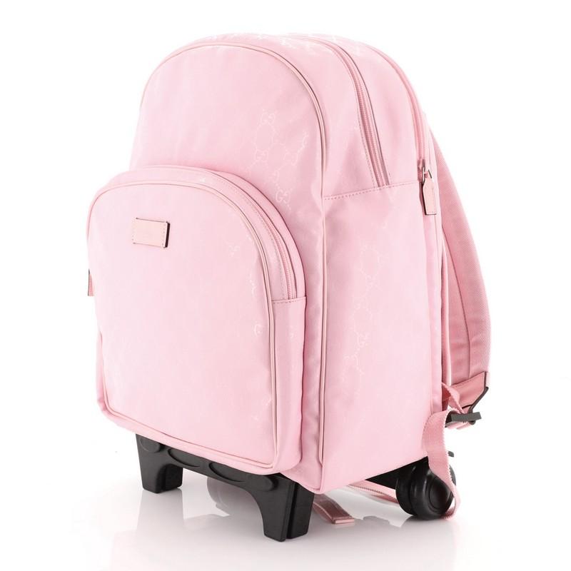 This Gucci Kid's Trolley Backpack GG Imprime, crafted from pink GG coated canvas, features adjustable shoulder straps, retractable handle, exterior front zip pocket and silver-tone hardware. Its zip closure opens to a pink nylon interior.