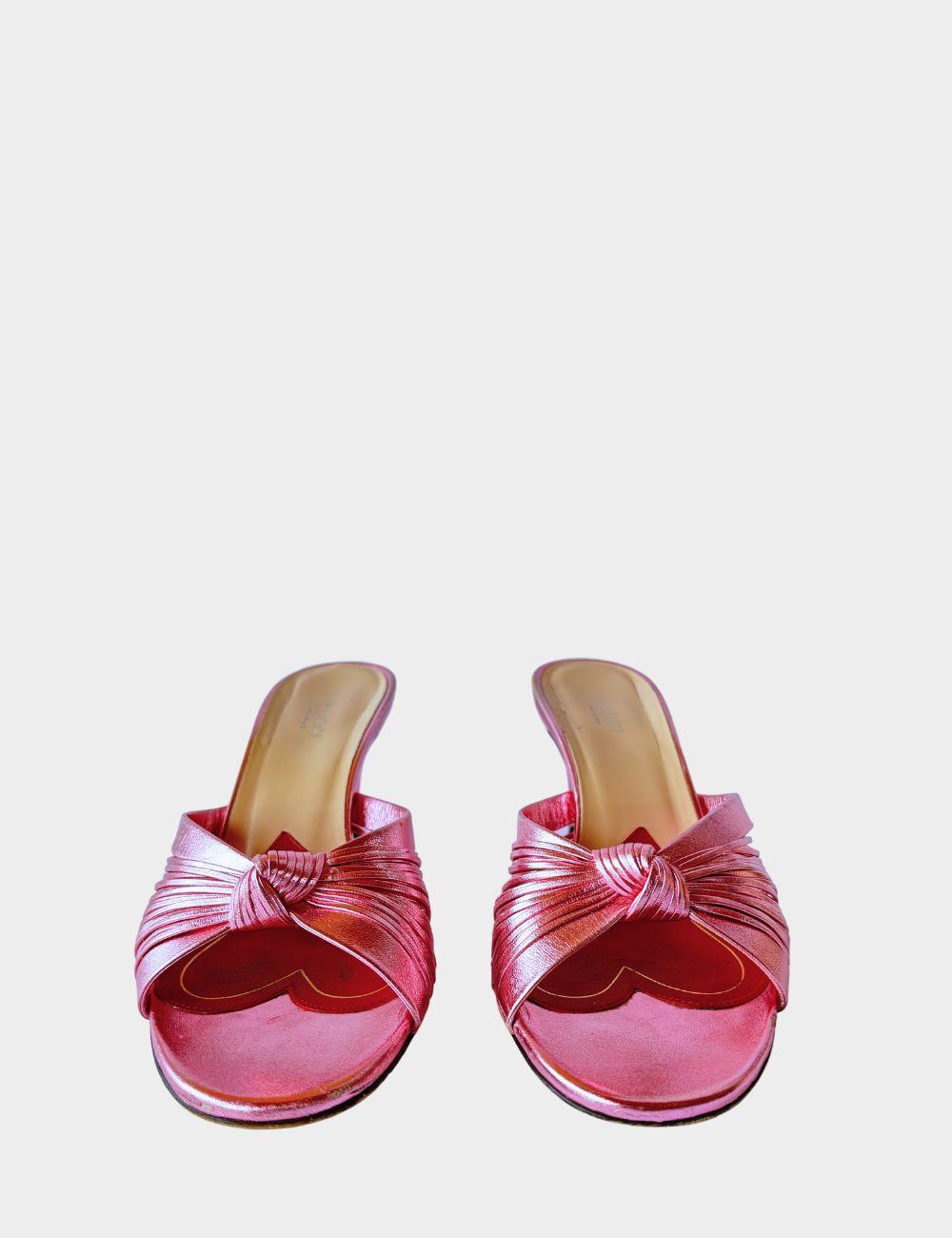 Step into feminine glamour with these Gucci metallic pink mules, designed with an elegant vintage-inspired silhouette. Featuring soft, knotted crossover straps, these slip-on heels are crafted from lustrous metallic leather that catches the light