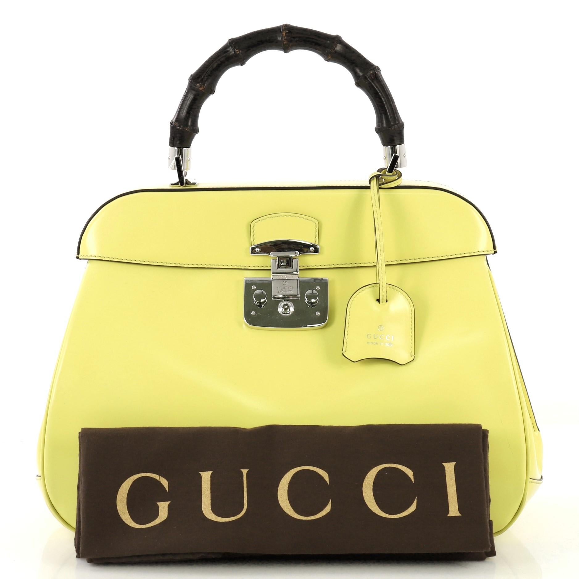 This Gucci Lady Lock Bamboo Top Handle Bag Leather Large, crafted in yellow leather, features a single loop bamboo handle and silver-tone hardware. Its flap with lady lock closure opens to a gray microfiber interior divided into two compartments