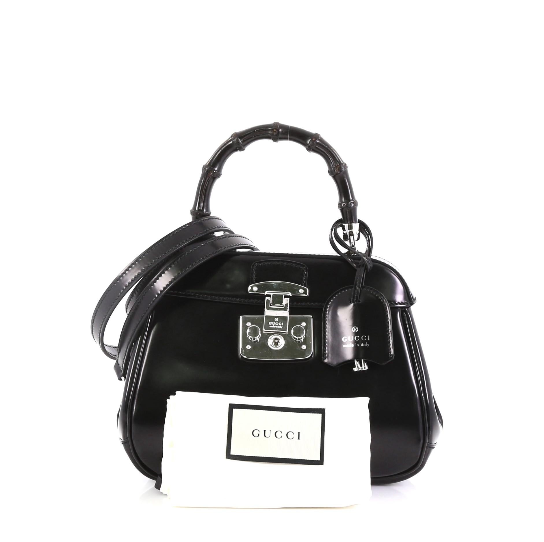 This Gucci Lady Lock Bamboo Top Handle Bag Leather Mini, crafted in black leather, features a single loop bamboo handle and silver-tone hardware. Its flap with lady lock closure opens to a purple suede interior with snap and zip pockets. 

Estimated