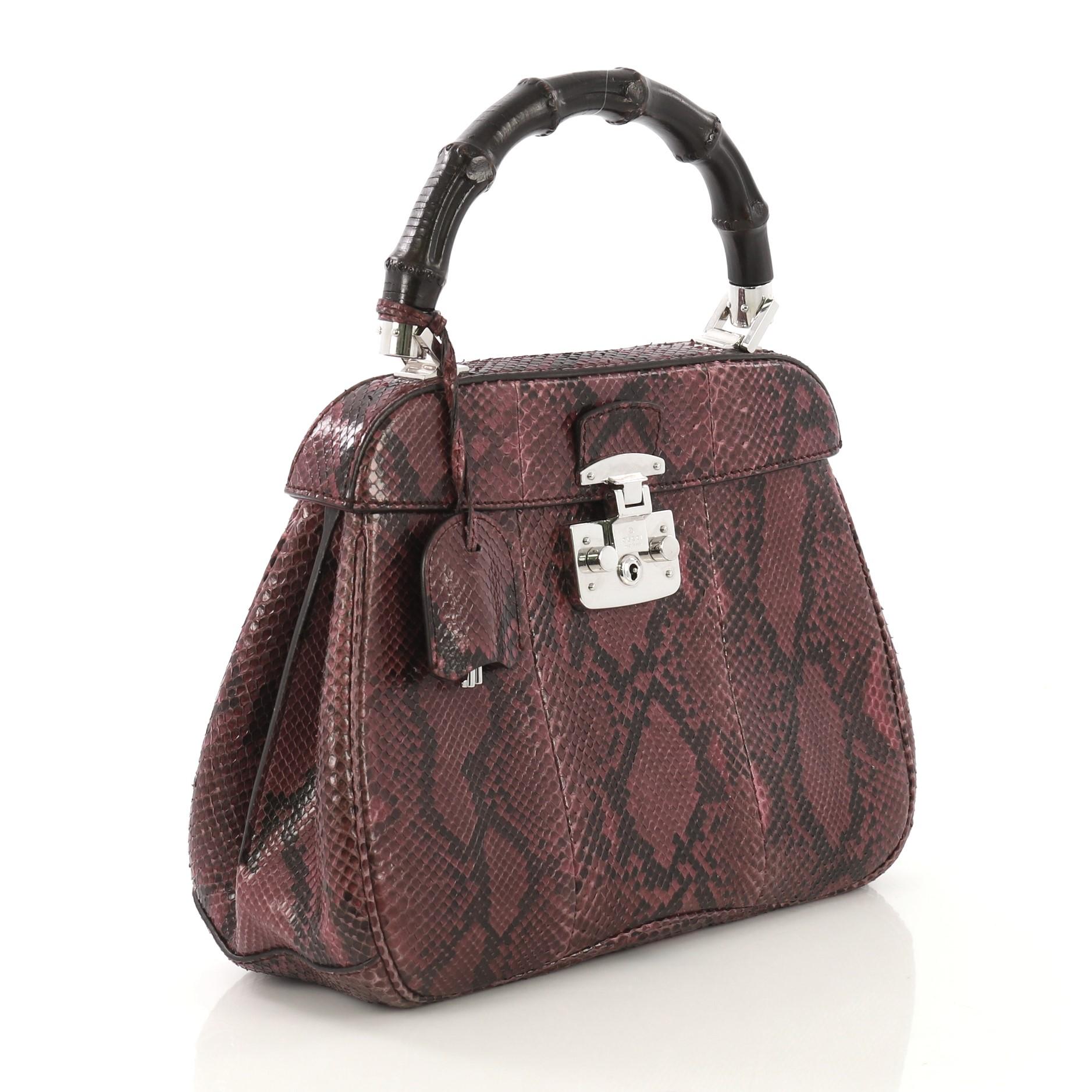 This Gucci Lady Lock Bamboo Top Handle Bag Python Medium, crafted in genuine purple python skin, features a single loop bamboo handle and silver-tone hardware. Its flap with lady lock closure opens to a purple suede interior divided into two