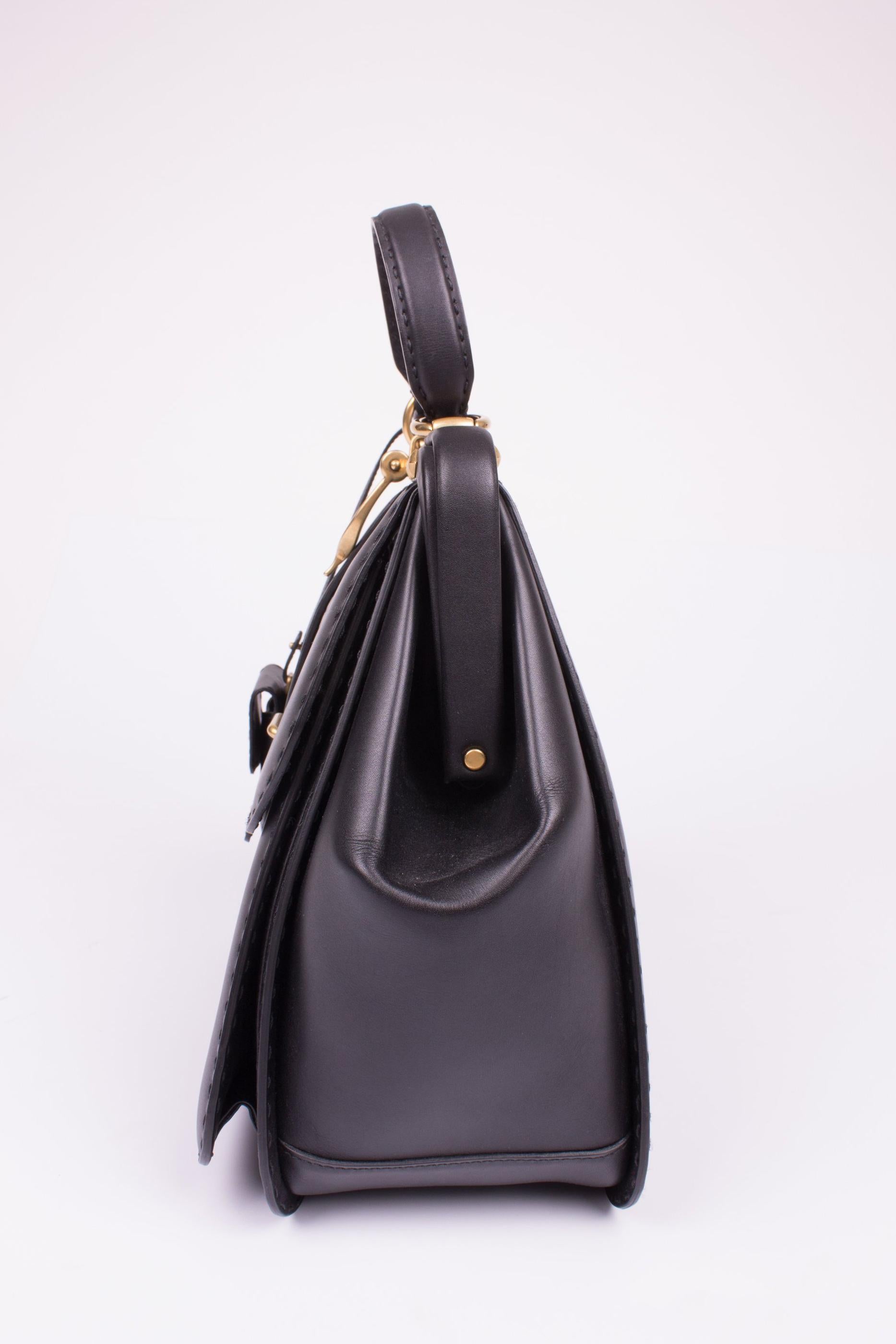 This is a very rare piece; number 146 out of 224 made. It is the Gucci Lady Stirrup Top Handle Bag!

The Gucci Lady Stirrup is often seen, but that's is the 'baguette' shape. This black bag has a little bit more length than the baguette. Executed in