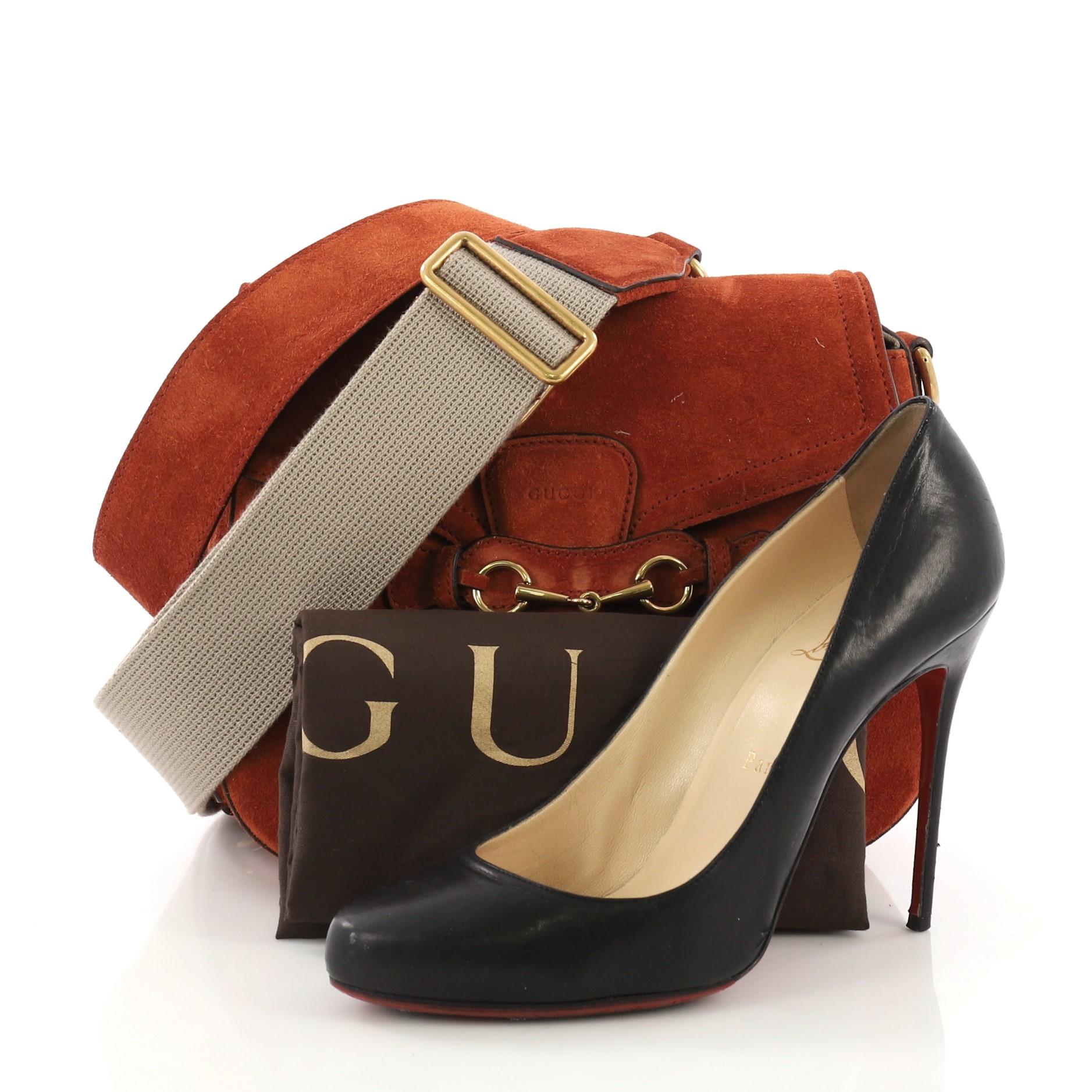 This Gucci Lady Web Shoulder Bag Suede Medium, crafted from orange suede, features an adjustable shoulder strap and aged gold-tone hardware. Its flap closure with horsebit buckle detail opens to a beige suede interior. **Note: Shoe photographed is