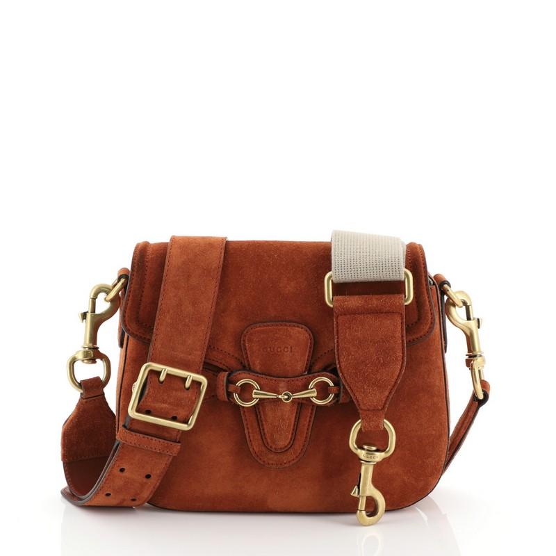 This Gucci Lady Web Shoulder Bag Suede Medium, crafted from orange suede, features an adjustable shoulder strap and aged gold-tone hardware. Its flap closure with horsebit buckle detail opens to a neutral suede interior. 

Estimated Retail Price: