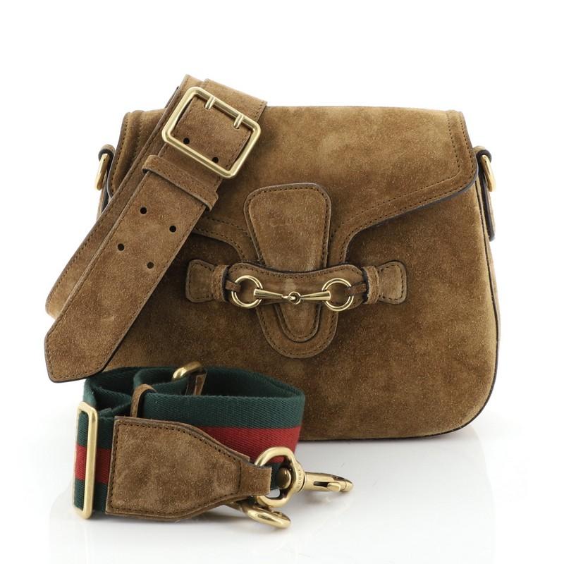 This Gucci Lady Web Shoulder Bag Suede Medium, crafted from brown suede, features an adjustable shoulder strap and aged gold-tone hardware. Its flap closure with horsebit buckle detail opens to a neutral suede interior. 

Estimated Retail Price: