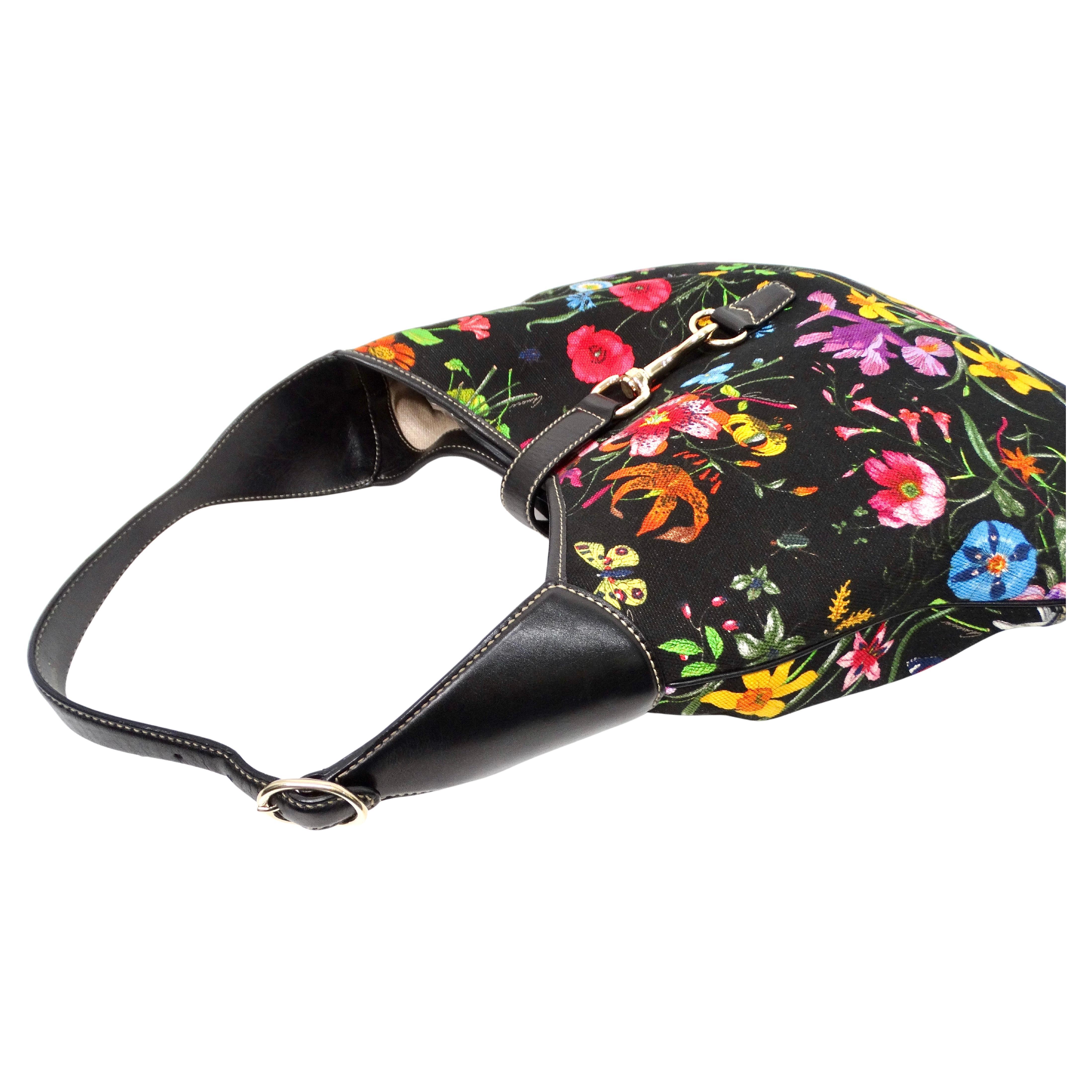 The Tom Ford for Gucci Large Flora Print Canvas & Black Leather Jackie Hobo Bag epitomizes modern luxury with its sophisticated blend of bold floral print canvas and sleek black leather accents. The bag features a striking floral pattern that