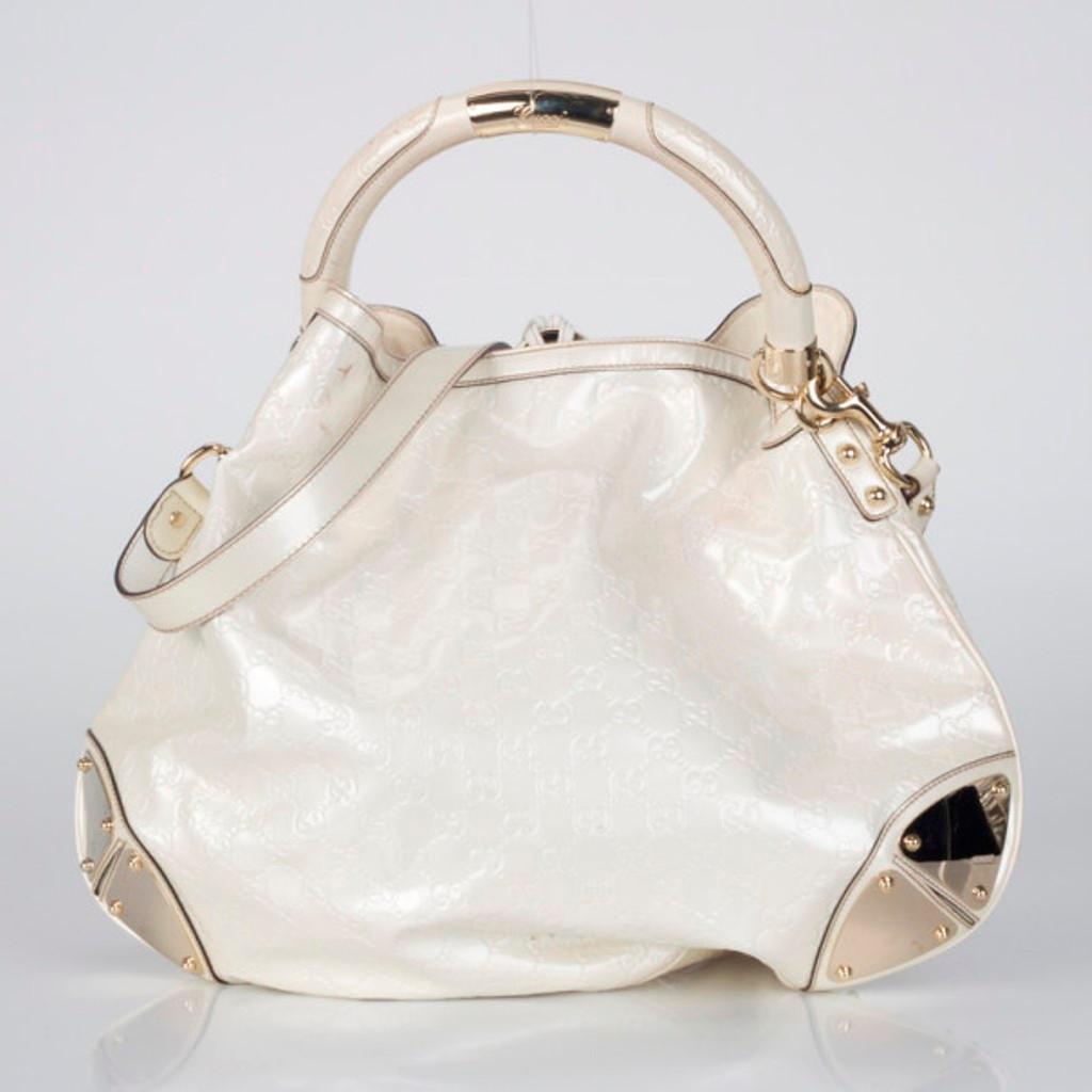 Gorgeous and versatile, this all white Gucci Indy is an ideal shoulder bag for everyday use. Crafted from pearl white patent leather, the exterior is accented with a Gucci logo handle, white tassels with bamboo and stud detailing. Its large interior