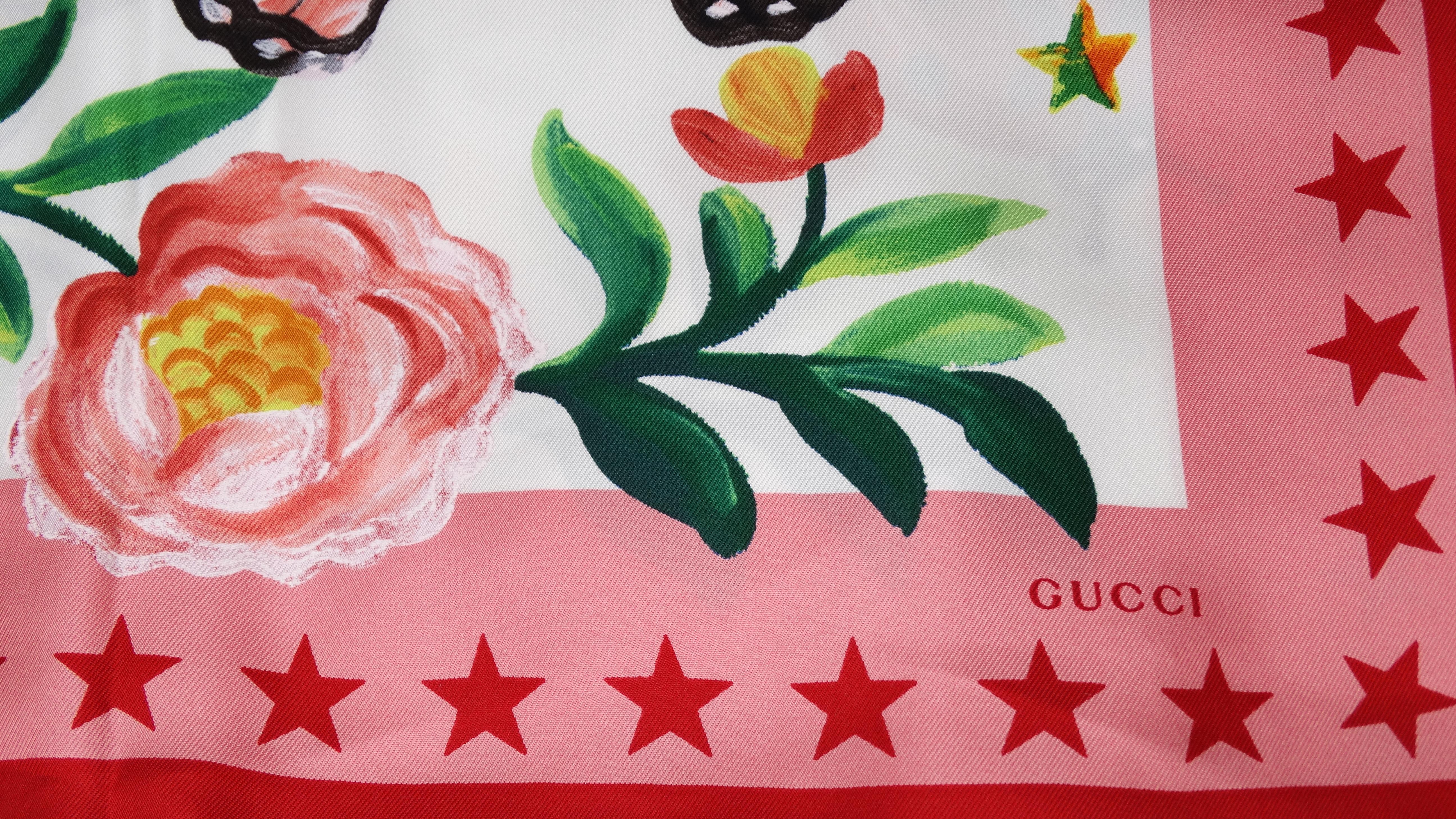 The perfect scarf to elevate your look! Circa 21st century, this Gucci silk scarf features a painted snake motif with a variety of insects, flowers, and stars throughout. A contrasting pink and red star pattern frames the trim with the phrase