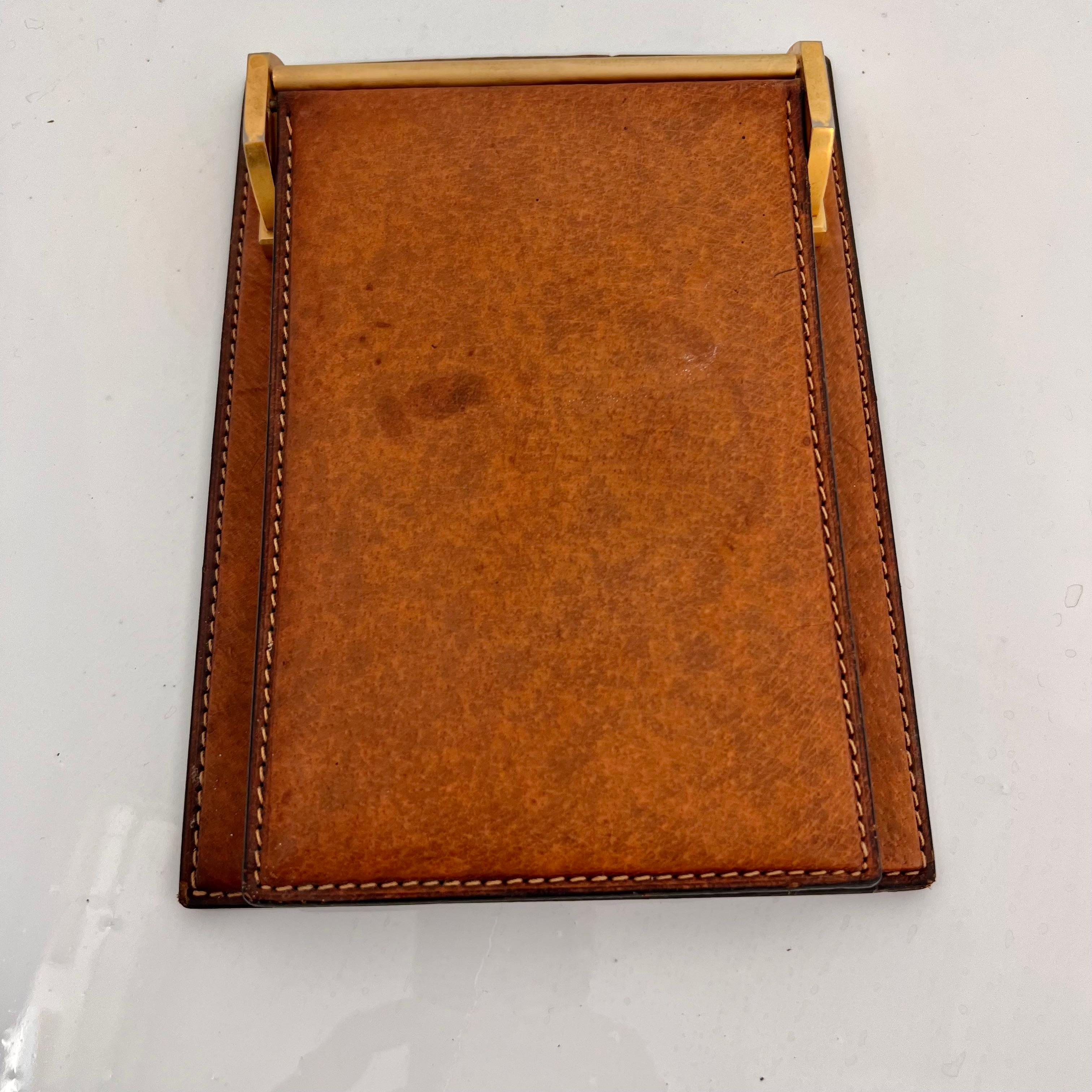 Handsome leather notepad by Gucci. Made in Italy, circa 1980s. Rich color to saddle leather with contrast stitching along the borders. Brass brackets holding leather flap. New 3