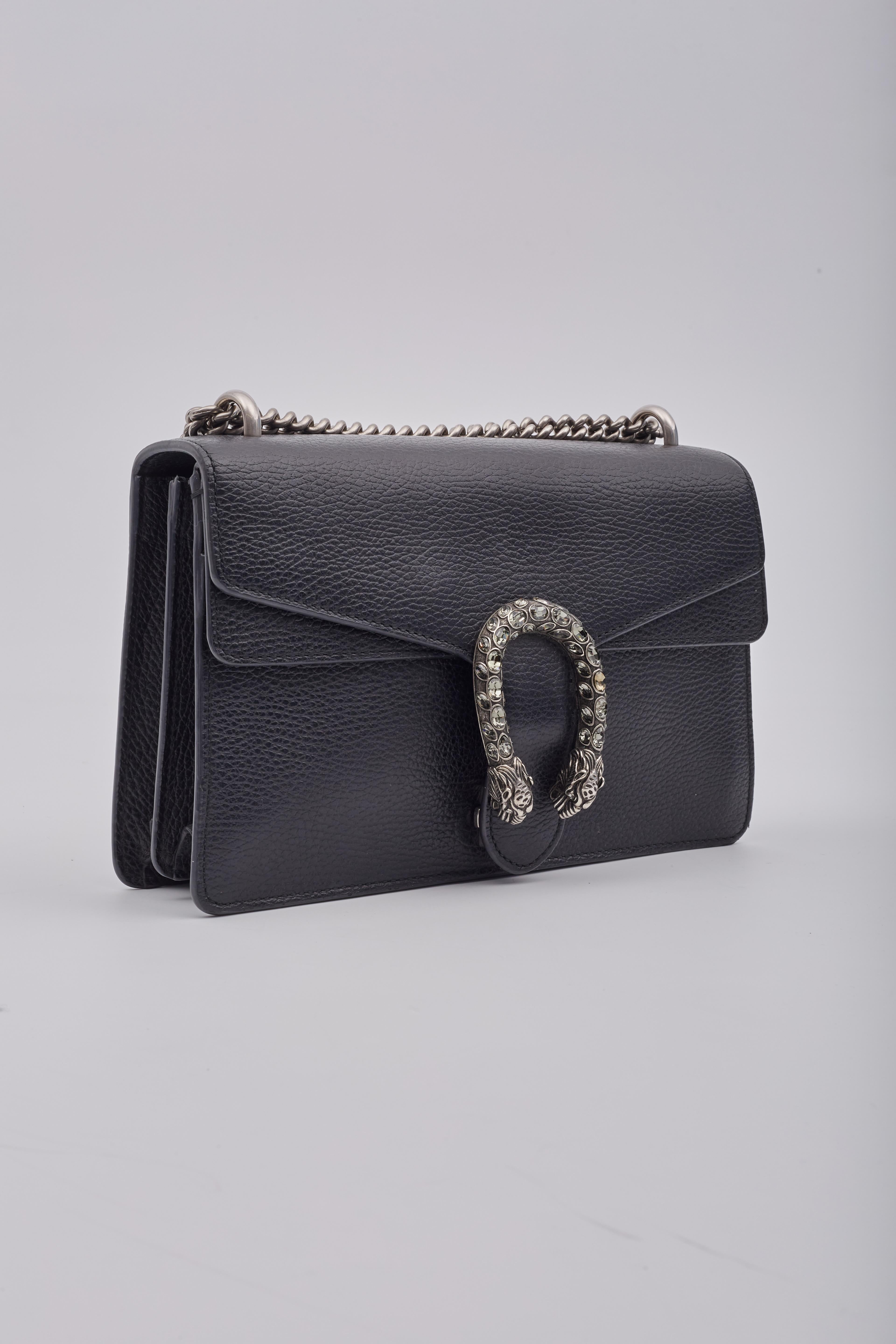 This Gucci shoulder bag is constructed from black textured leather, showcasing the strass-embellished Dionysus tiger head detail on the front. The bag is adorned with silver-tone hardware, chain-link shoulder strap and snap closure. The front flap