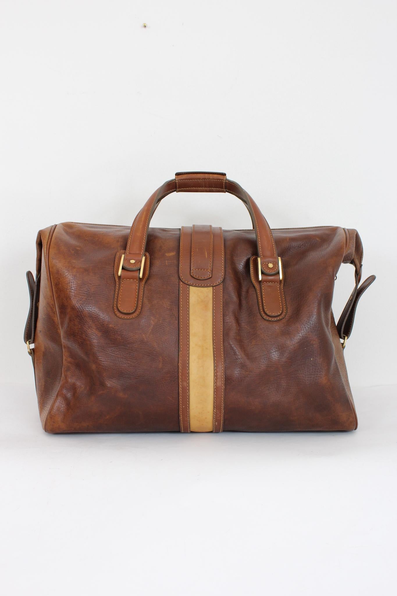 Gucci vintage 80s duffle bag. Made of excellent brown leather, with lighter shades. The bag features brass buckles and trims. The double side buckle can adjust the size of the bag. The interior is made up of a logoed fabric lining, a little faded by