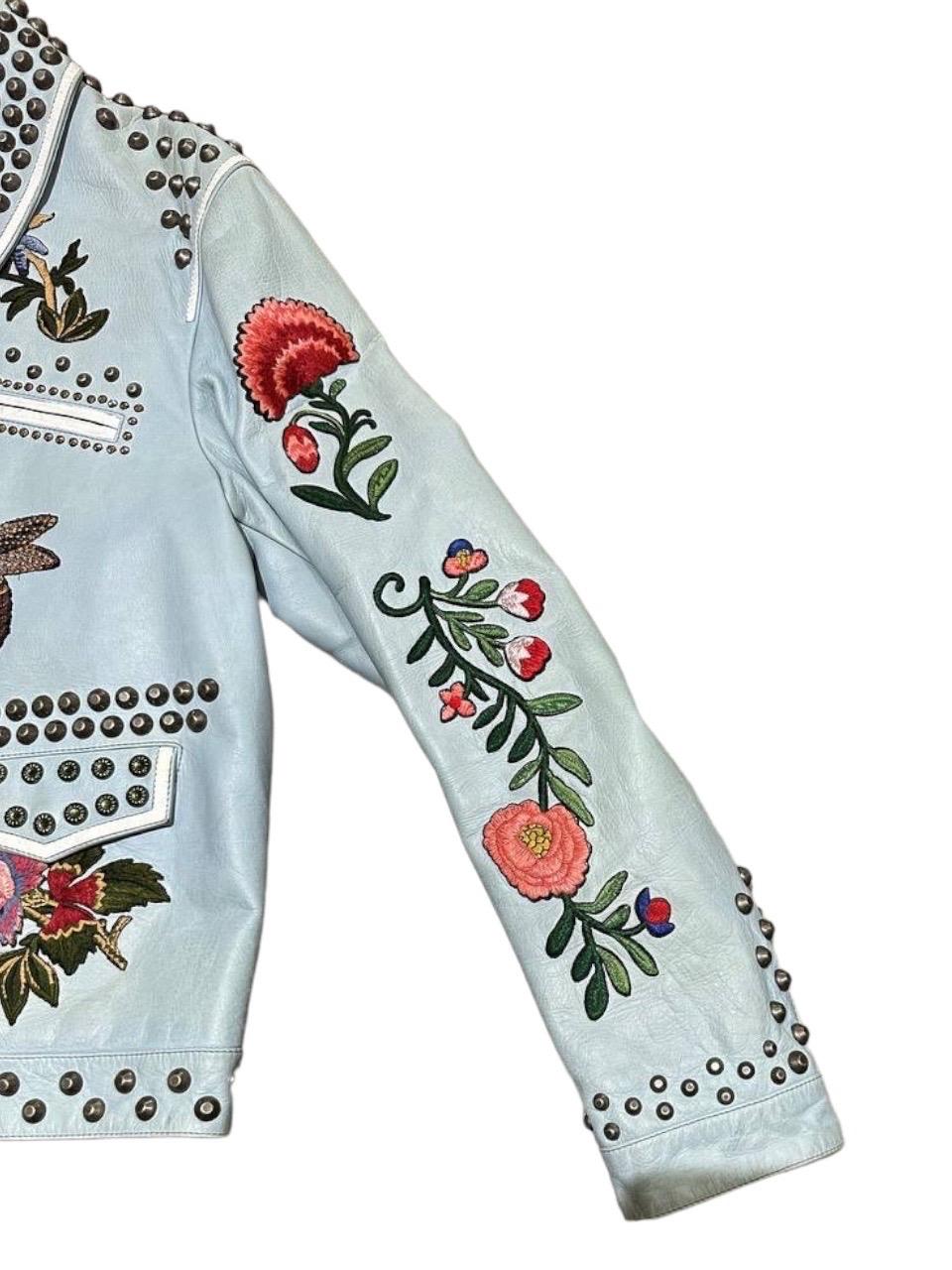 Gucci signed jacket, made of light blue leather with silver hardware. Equipped with studs and hand-embroidered inserts. Equipped with zip closure, with 4 side pockets, two of which with zip. Internally covered in quilted floral fabric. The product