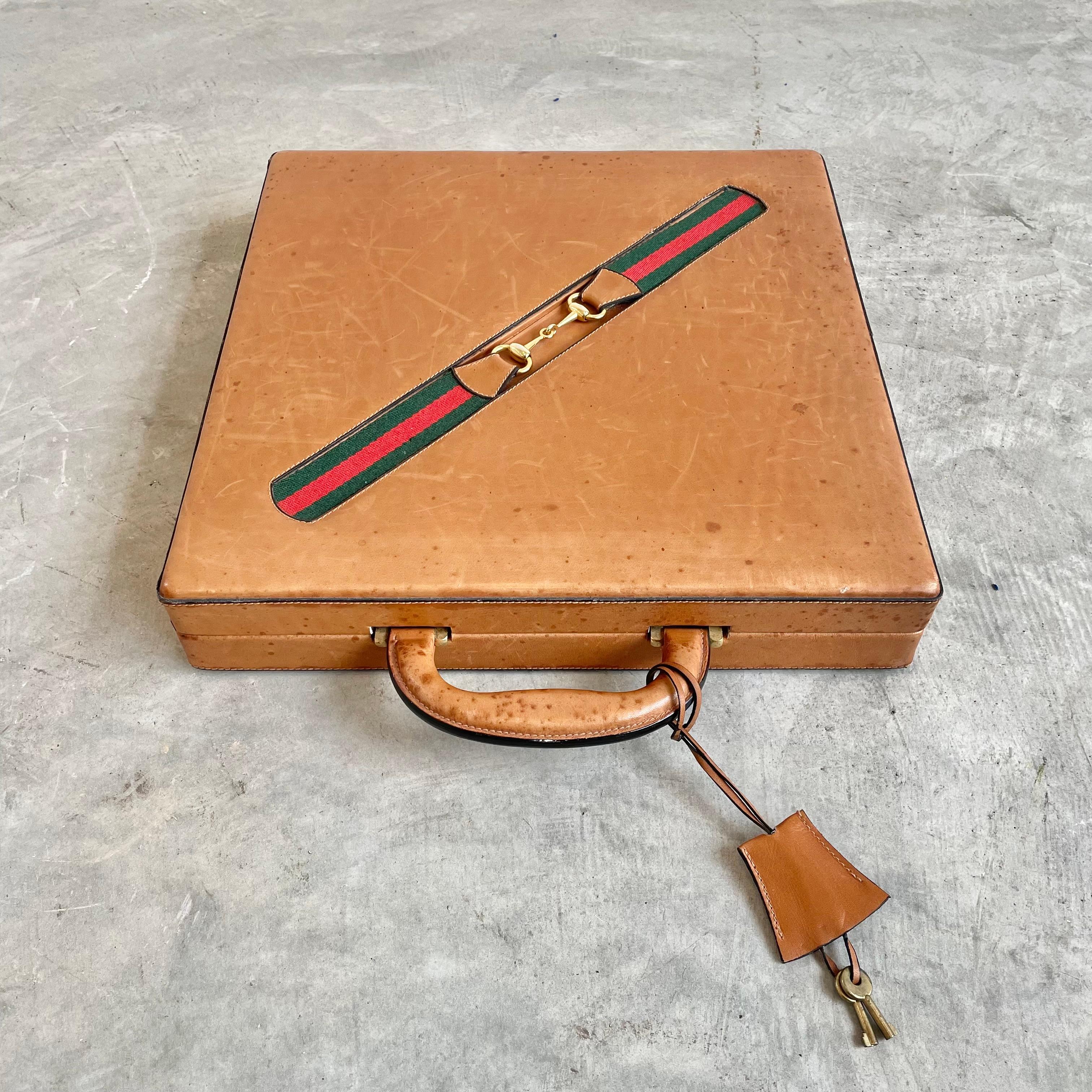 Vintage portable Gucci leather game case with chess, checkers, poker and dominoes. Wood framed case wrapped in elegant saddle leather with the iconic Gucci red and green strap across the front and fastened in the middle with a classic Gucci horse