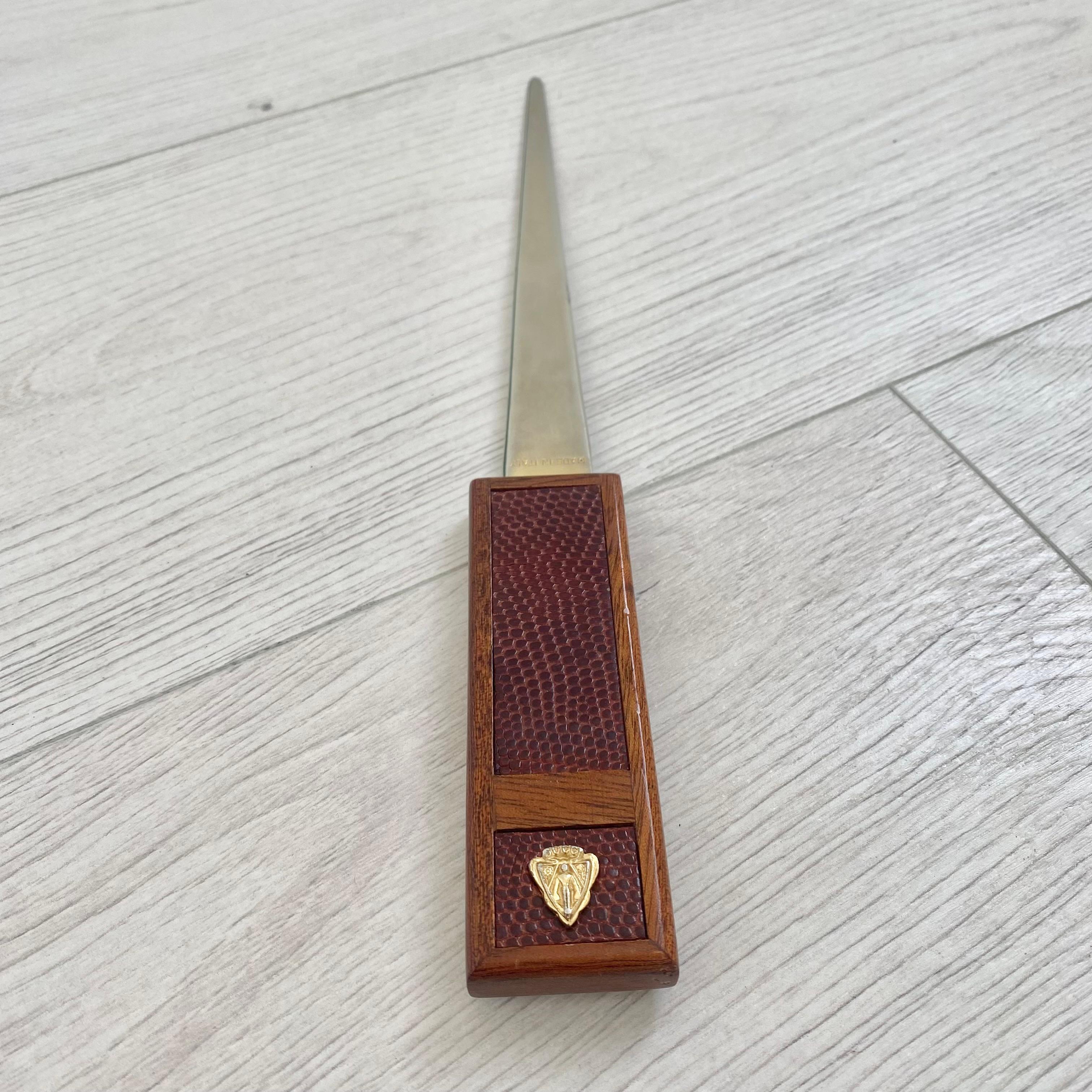 Handsome Gucci letter opener made in Italy, circa 1980s. Rectangular wood handle with inlaid burgundy leather. Gucci crest on bottom center. Long chrome/brass blade extending from handle. Stamped 