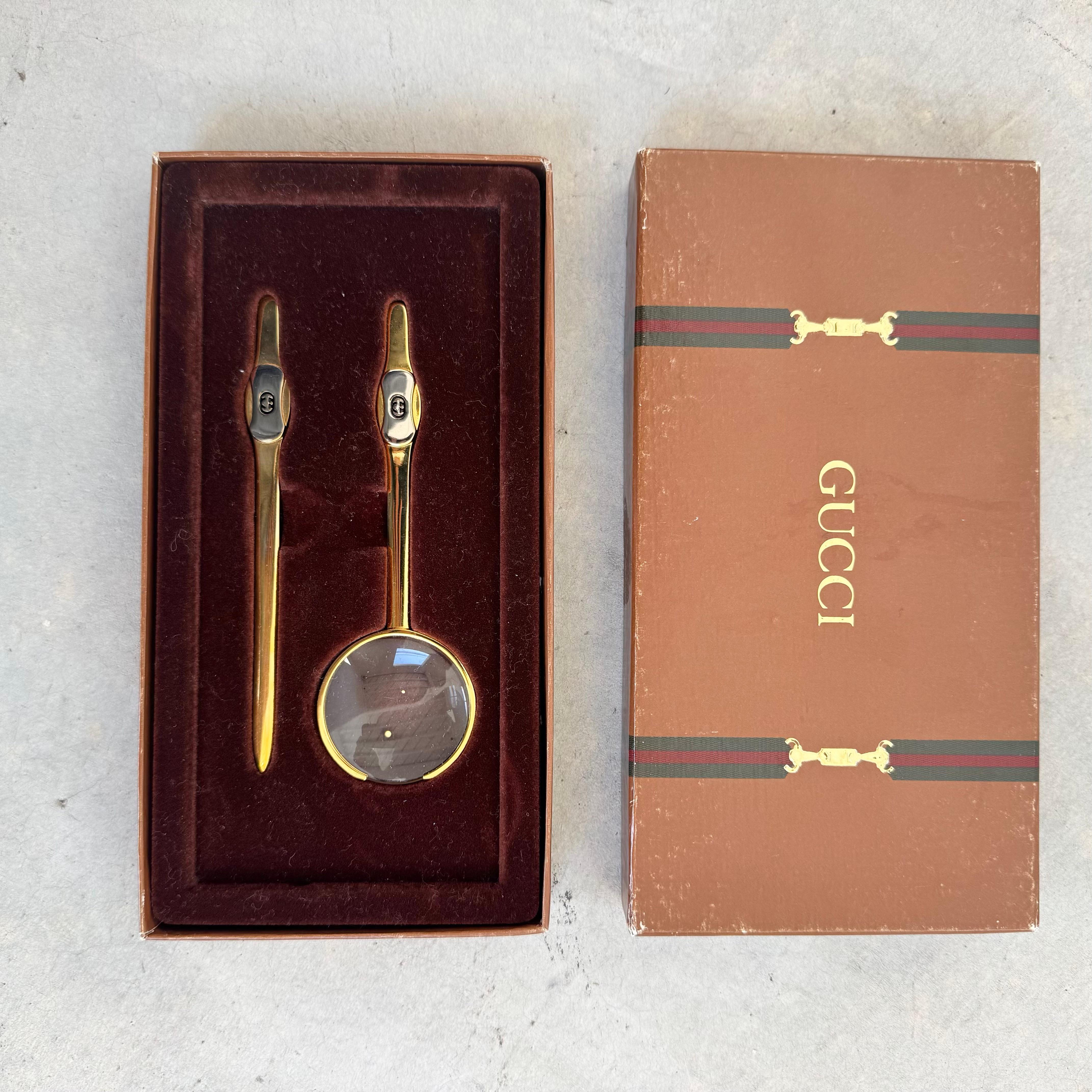 Add a sophisticated touch to your home office or workspace with this vintage Gucci desk set. Includes a vintage magnifying glass and a letter opener in solid brass, complete with original packaging. Brass rim of magnifying glass is opened on the