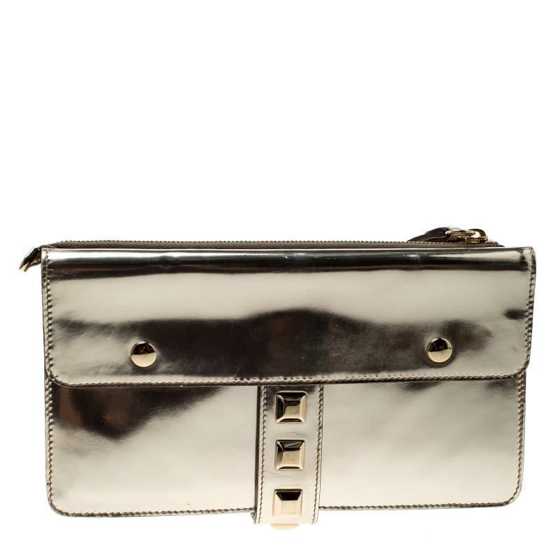 Crafted from light gold patent leather and styled with gold-tone studs to the front, this Gucci evening wristlet is that handy accessory that you'll love to carry for parties and evening outings. It features two buckled flap pockets on the front