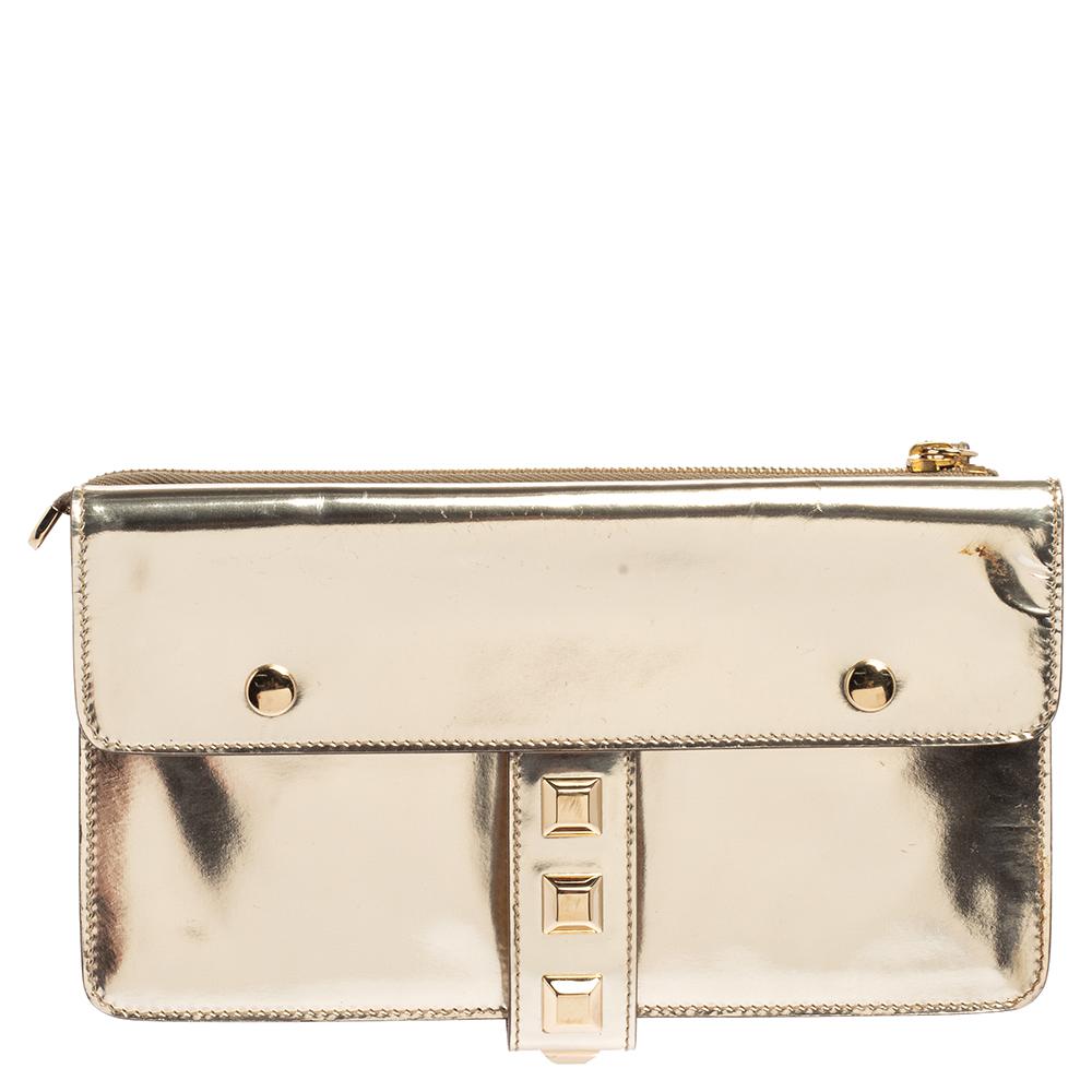 Crafted from light gold patent leather and styled with gold-tone studs to the front, this Gucci evening wristlet is that handy accessory that you'll love to carry for parties and evening outings. It features two buckled flap pockets on the front