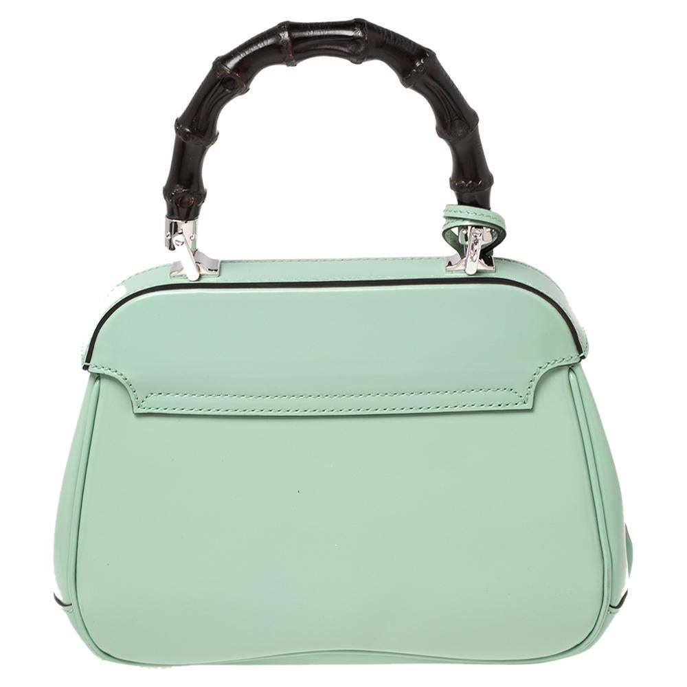 Featuring the iconic Lady Lock, this top handle bag is from Gucci. This bag is crafted from light green-hued leather and features a signature bamboo top handle. The push-lock closure opens to a suede-lined interior that houses an open compartment.