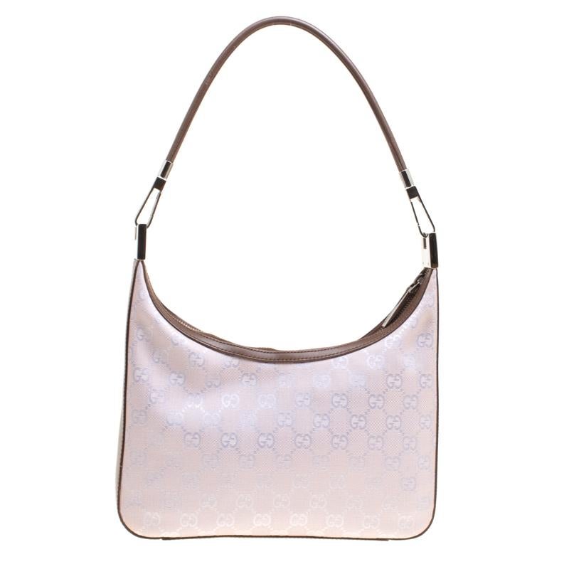 It is rare to find a piece as gorgeous as this Gucci shoulder bag. It has been crafted from lilac GG canvas and styled with leather trims that outlines it. The top zip closure leads the way to nylon interiors that will hold all your belongings, and