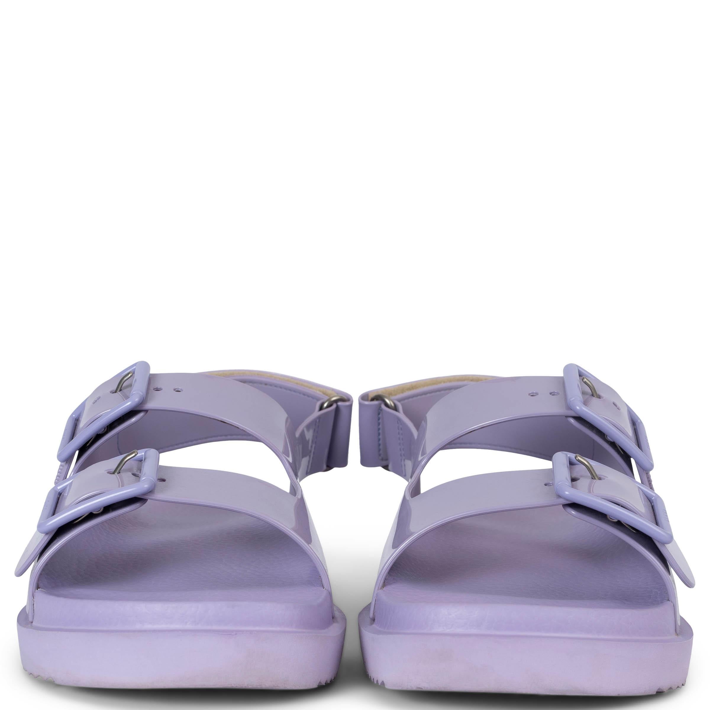 These 100% authentic Gucci Isla Dad sandals are crafted from Lapis (lilac) rubber with tonal hardware, offering a chic and comfortable design. The iconic double-G logo, reimagined with tonal studs, adds a subtle nod to Gucci's '70s archives.