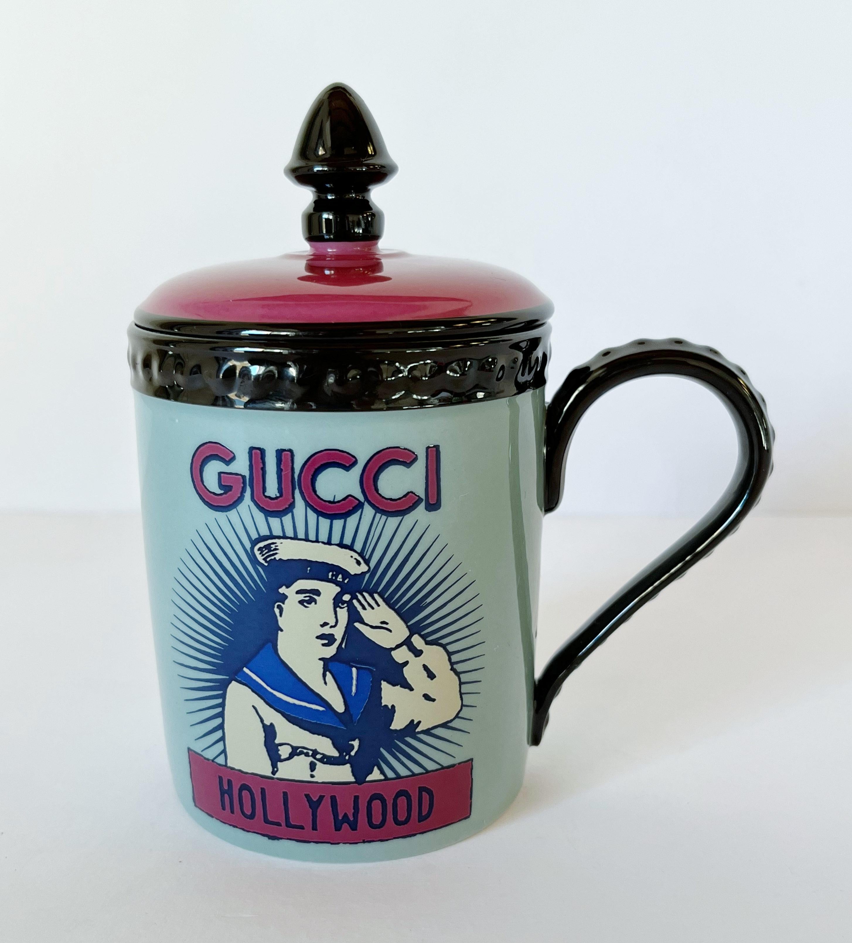 Taza de porcelana con tapa de inspiración marítima de Gucci en colores azul claro y rosa, con estampado marinero de Hollywood en una cara y detalle de ancla con el mundo 
