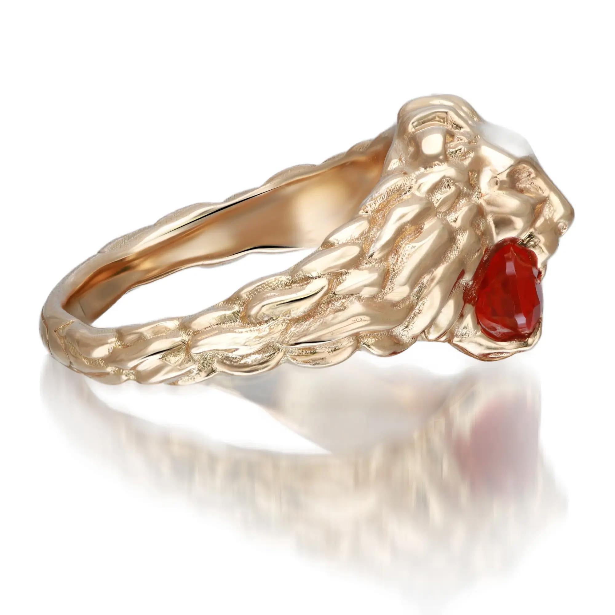 This contemporary GUCCI lion head ring is crafted in 18K Yellow Gold. The ring features a lion head motif embellished with a faceted orange fire opal stone and round cut diamonds set as the eyes weighing approximately 0.01 carat. Bold and