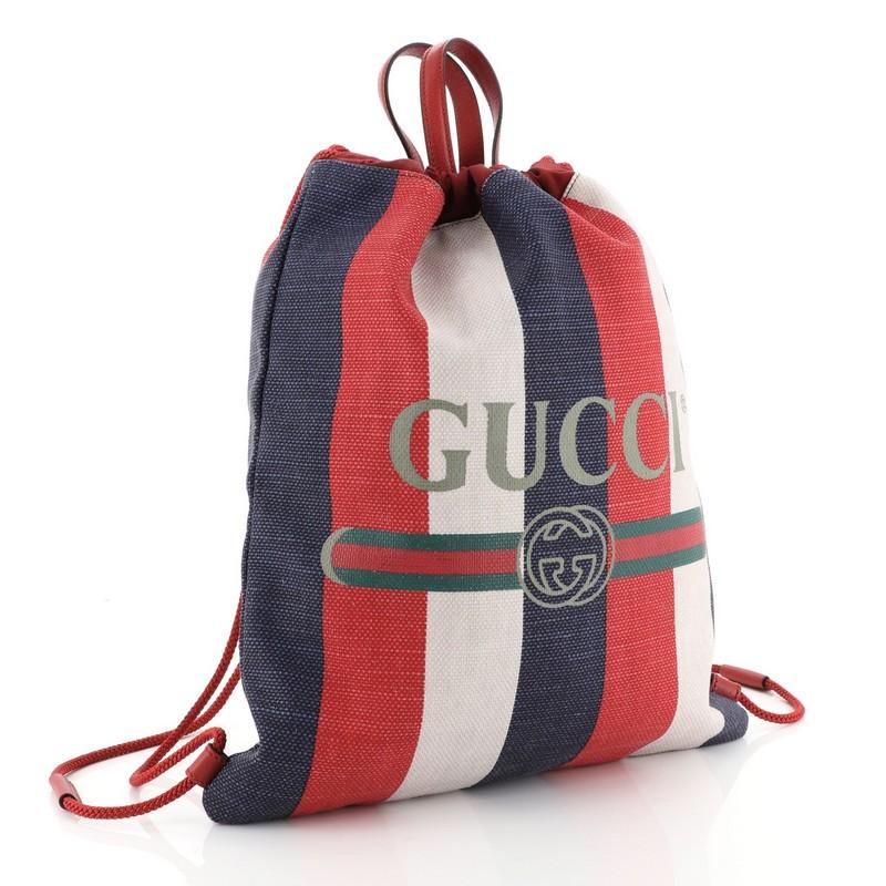 This Gucci Logo Drawstring Backpack Striped Raffia Large, crafted in white, blue, and red multicolor leather, features dual leather top handles and rope straps that double function as a drawstring, and aged gold tone hardware. Its drawstring closure