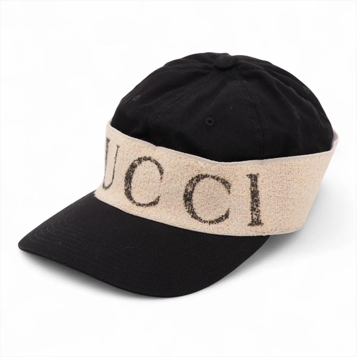 Il berretto in cotone con logo Gucci in nero combina funzionalità sportiva e stile di lusso. Realizzato in cotone pregiato, presenta un elegante corpo nero accentuato da una fascia beige ornata dall'iconico logo Gucci, che aggiunge un tocco di