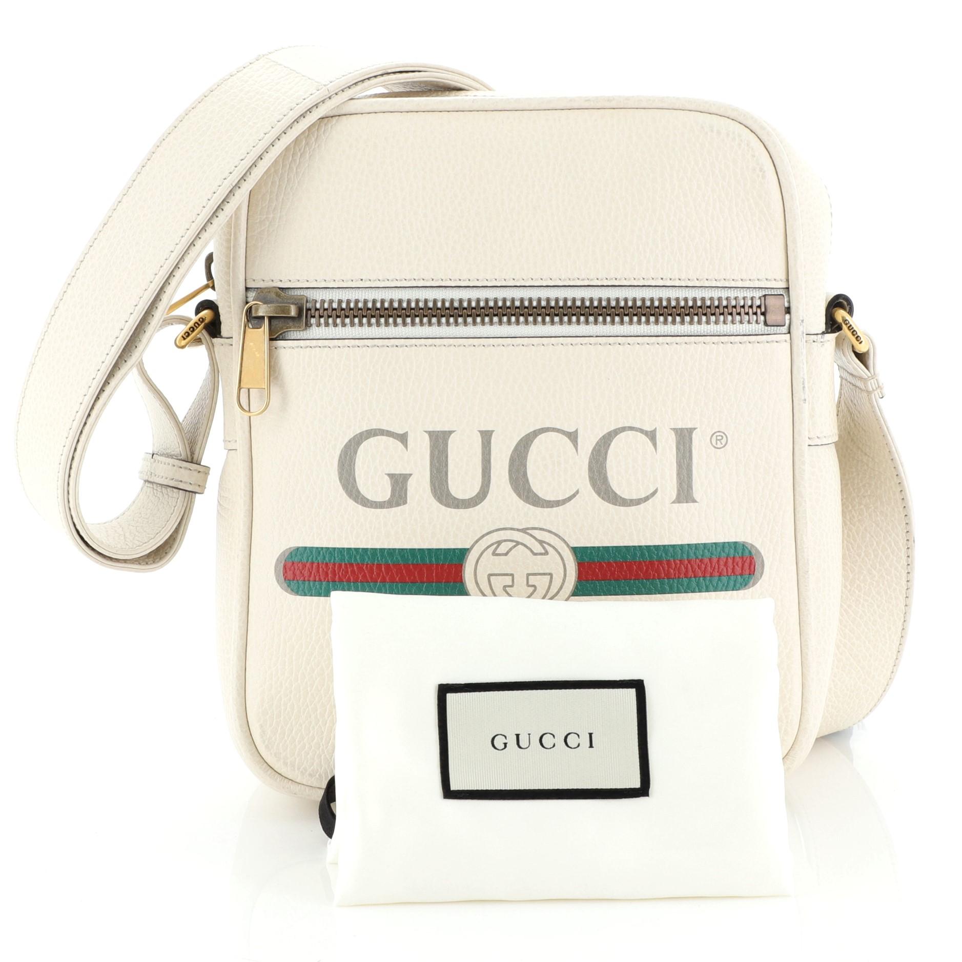 This Gucci Logo Zip Messenger Bag Printed Leather Small, crafted from white printed leather, features adjustable leather strap, front zip pocket, printed Gucci vintage logo, and aged gold-tone hardware. Its top zip closure opens to a neutral canvas