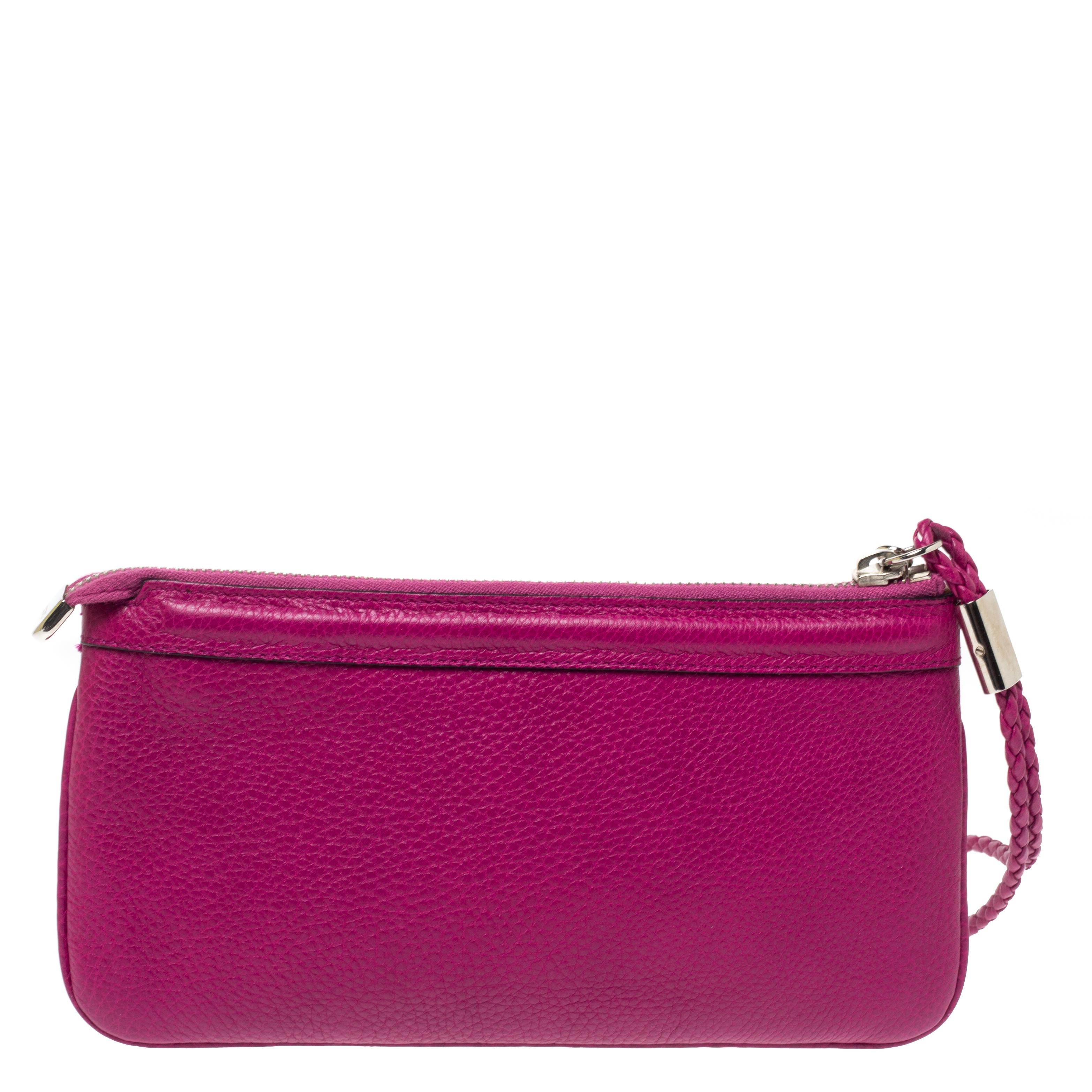 Have all eyes on you when you flaunt this stunner of a clutch by Gucci. Crafted from leather, it has a breathtaking magenta shade and a lovely shape. The clutch is equipped with a wristlet strap and a fabric interior that will hold your cards, cash