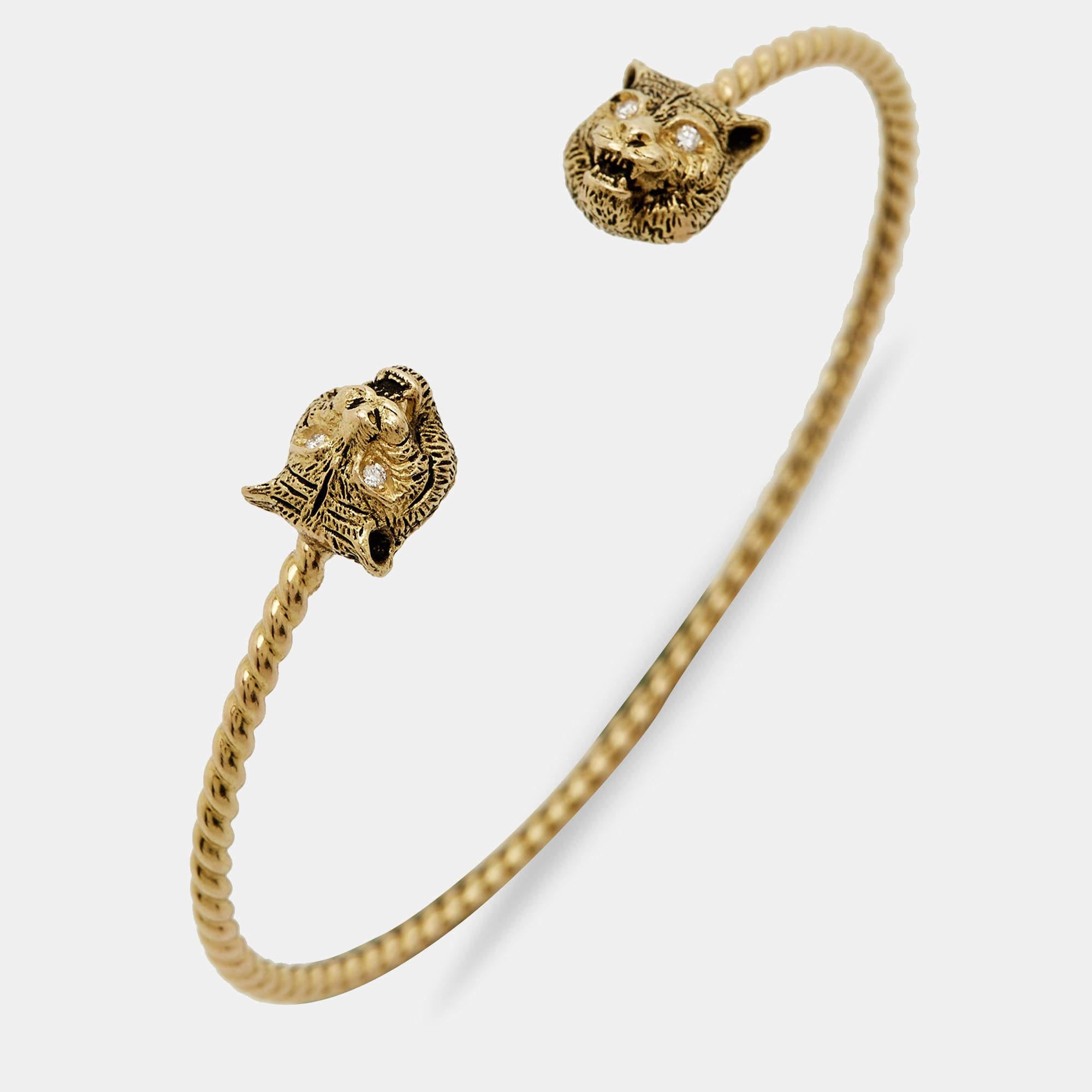 The Gucci Marche des Merveilles cuff bracelet is a luxurious and captivating piece of jewelry. Crafted from 18K yellow gold, it features intricate feline head motifs adorned with sparkling diamonds. The design exudes elegance and sophistication,