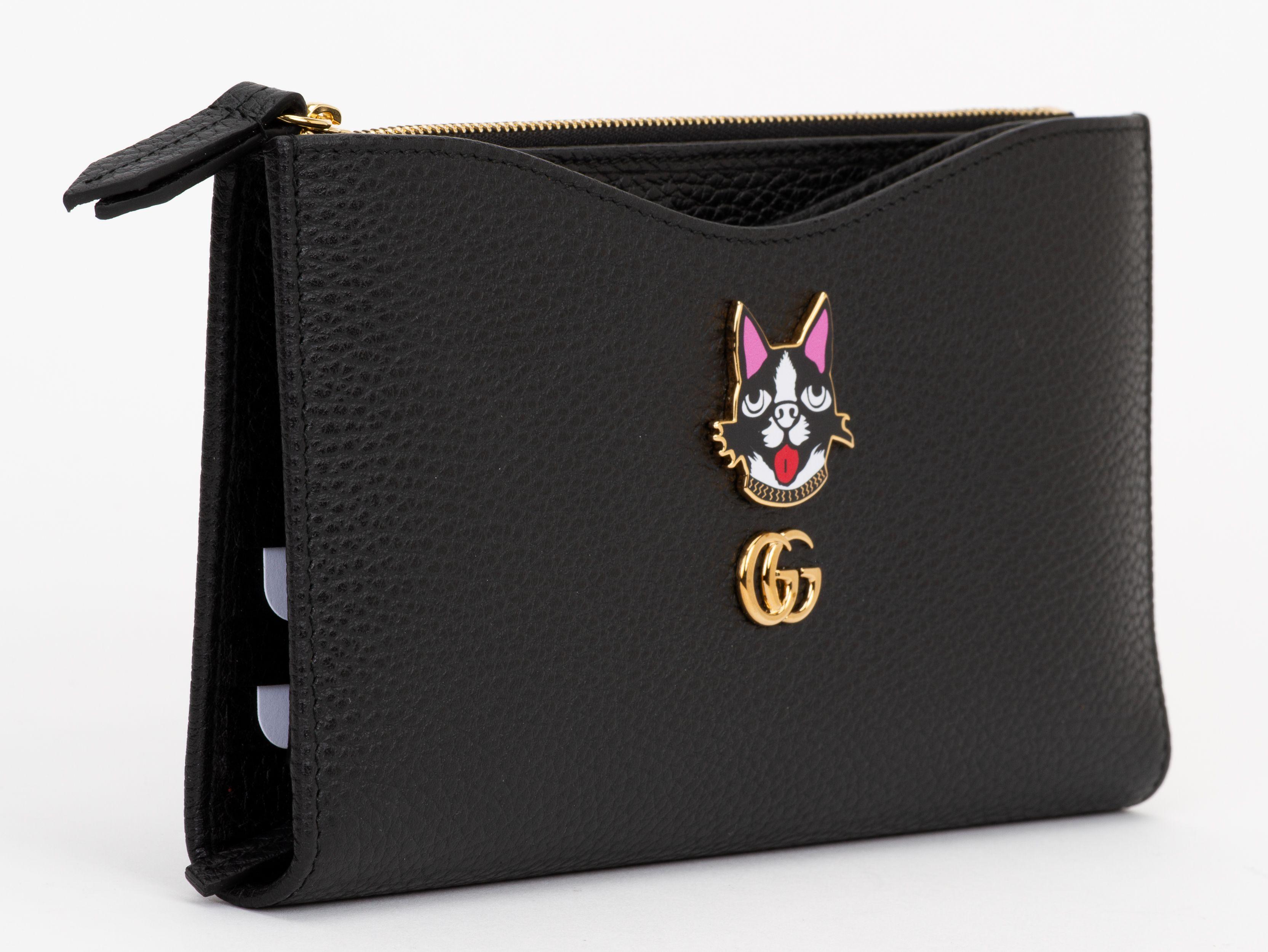 La maxi pochette Gucci Marmont Leather è in pelle nera con inserto per carte di credito rimovibile. Il gatto Bosco è presente sul davanti insieme a GG color oro.