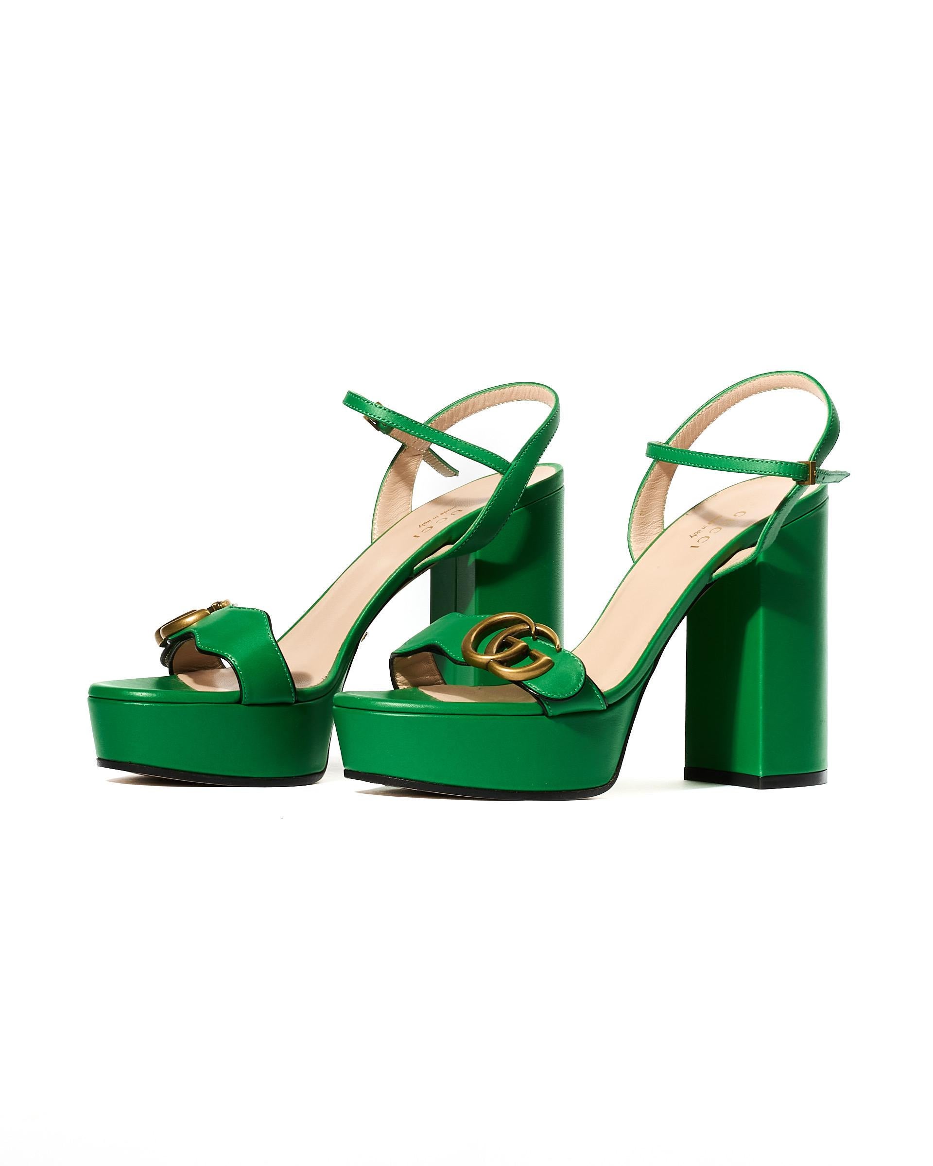 Sandali firmati Gucci, modello “Marmont”, realizzato in pelle colore verde con hardware oro. Presenta una chiusura cn piccola fibbia alla caviglia. Dettaglio logo GG sulla parte superiore della fascia anteriore.  Tacco alto 11 cm. Numero