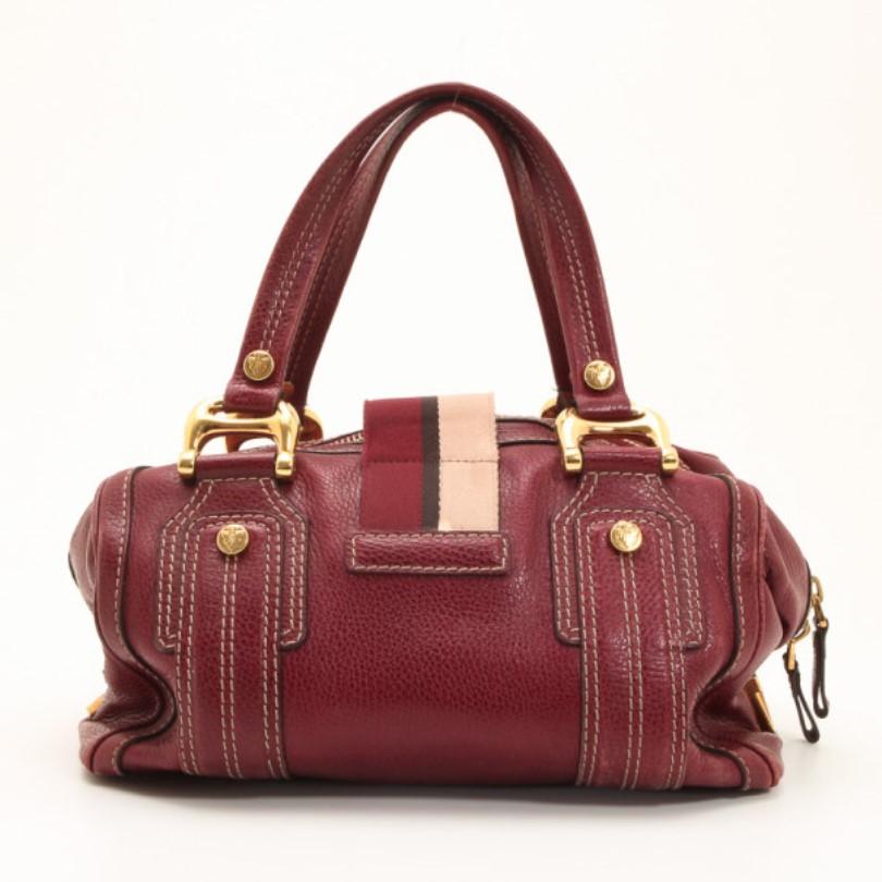 The iconic details on the Gucci Aviatrix make it an interesting and must-have Gucci handbag. This satchel combines soft grained maroon leather with Gucci’s classic red and pink fabric striped trim. The Aviatrix’s exterior features Gucci’s signature