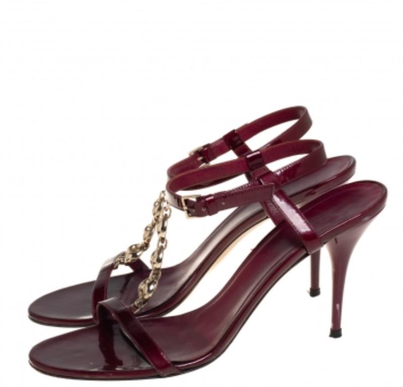 How can one not fall in love with these stunning sandals by Gucci! They've been beautifully crafted from maroon patent leather and styled with gold-tone chain T-straps on the vamps. The sandals carry open toes, ankle straps with buckle fastening,