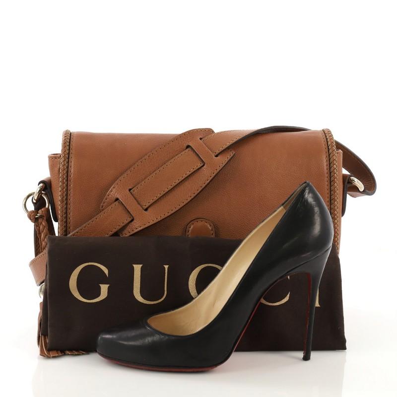 This Gucci Marrakech Messenger Bag Leather Medium, crafted from brown leather, features adjustable leather strap, woven leather trim, tassel with G detailing, and gold-tone hardware. Its flap with snap hook closure opens to a beige fabric interior