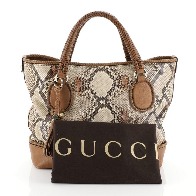 This Gucci Marrakech Tote Python Medium, crafted from genuine brown python skin, features, dual braided handles with leather tassels, braided leather trims, and gold-tone hardware. Its hook clasp closure opens to a brown leather interior with zip