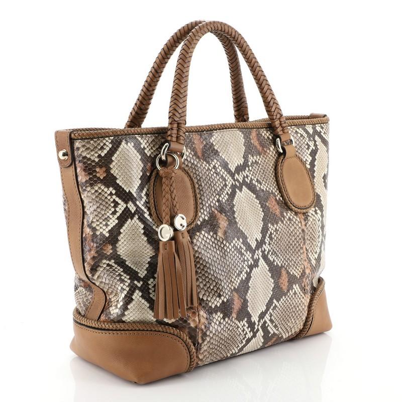 This Gucci Marrakech Tote Python Medium, crafted from genuine brown python skin, features, dual braided handles with leather tassels, braided leather trims, and gold-tone hardware. Its hook clasp closure opens to a brown leather interior with zip