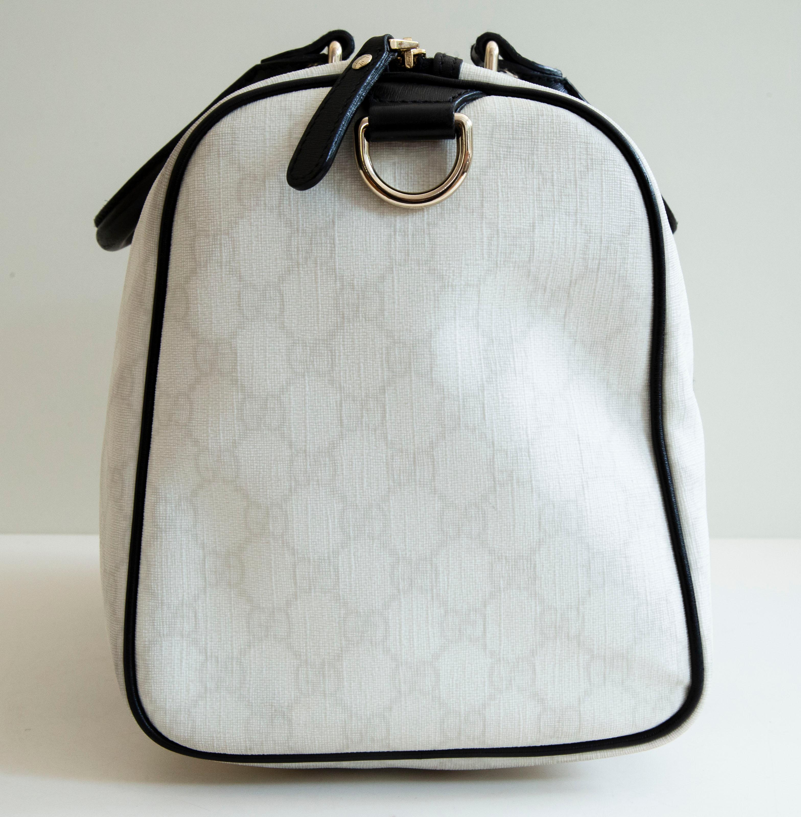 Gucci Boston bag made of white-off GG coated canvas with black leather trim and light gold-toned hardware. The interior is lined with black fabric and next to the major compartment, it features a side pocket. The exterior is in very good condition
