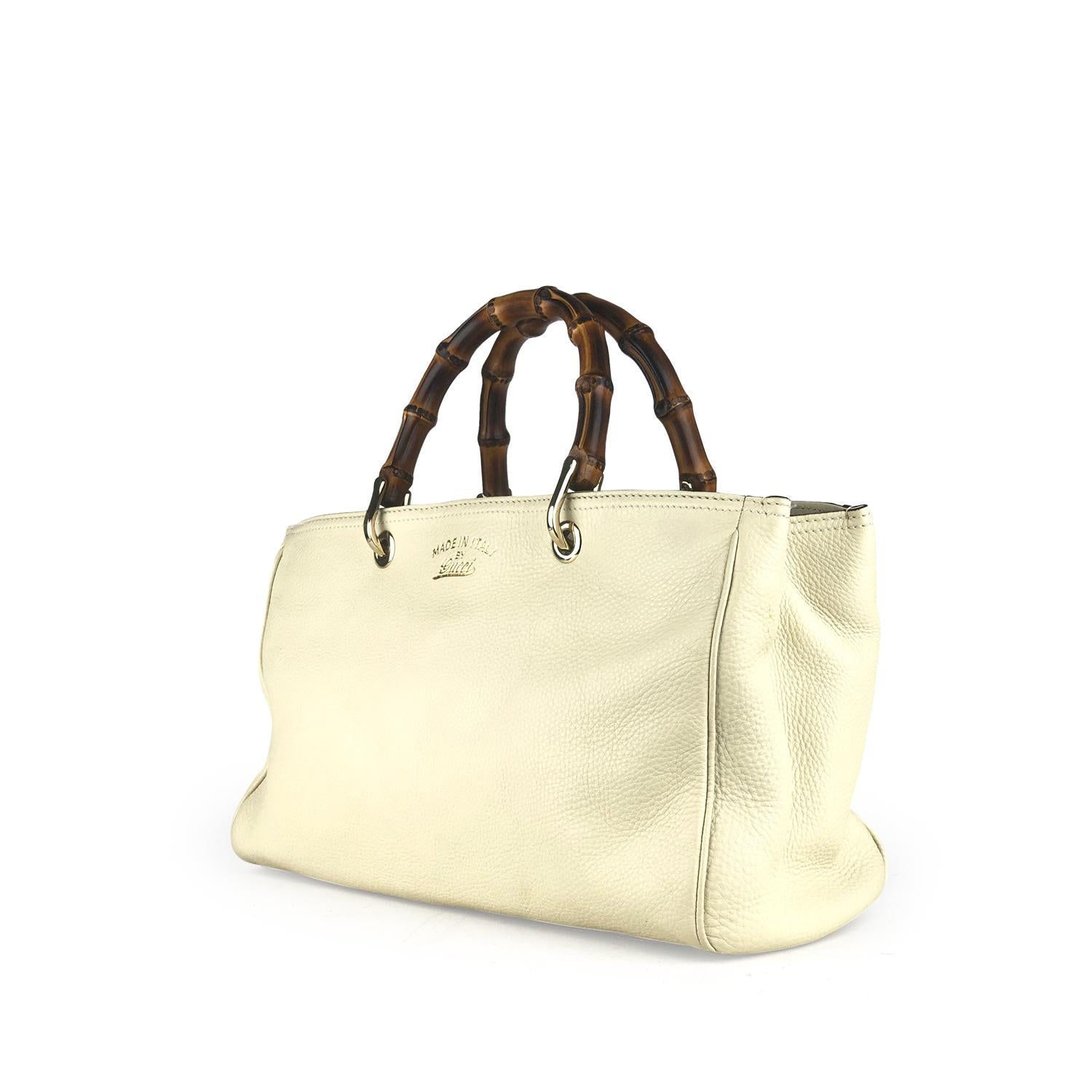 Cream leather Gucci Medium Soho tote with

– Brushed gold-tone hardware
– Dual bamboo top handles
– Single flat shoulder strap
– Protective feet at base, tonal canvas lining, three interior compartments; one with zip closure, four pockets at