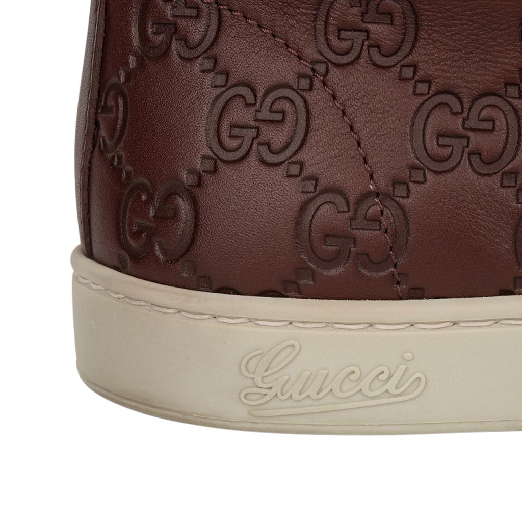 Guaranteed authentic Gucci mens high top sneakers.
Burgundy logo embossed high top leather sneaker.
Grosgrain ribbon in chardonnay and green along sides.
Gucci logo on edge.
Some wear on soles.  See images.
Comes with signature box and