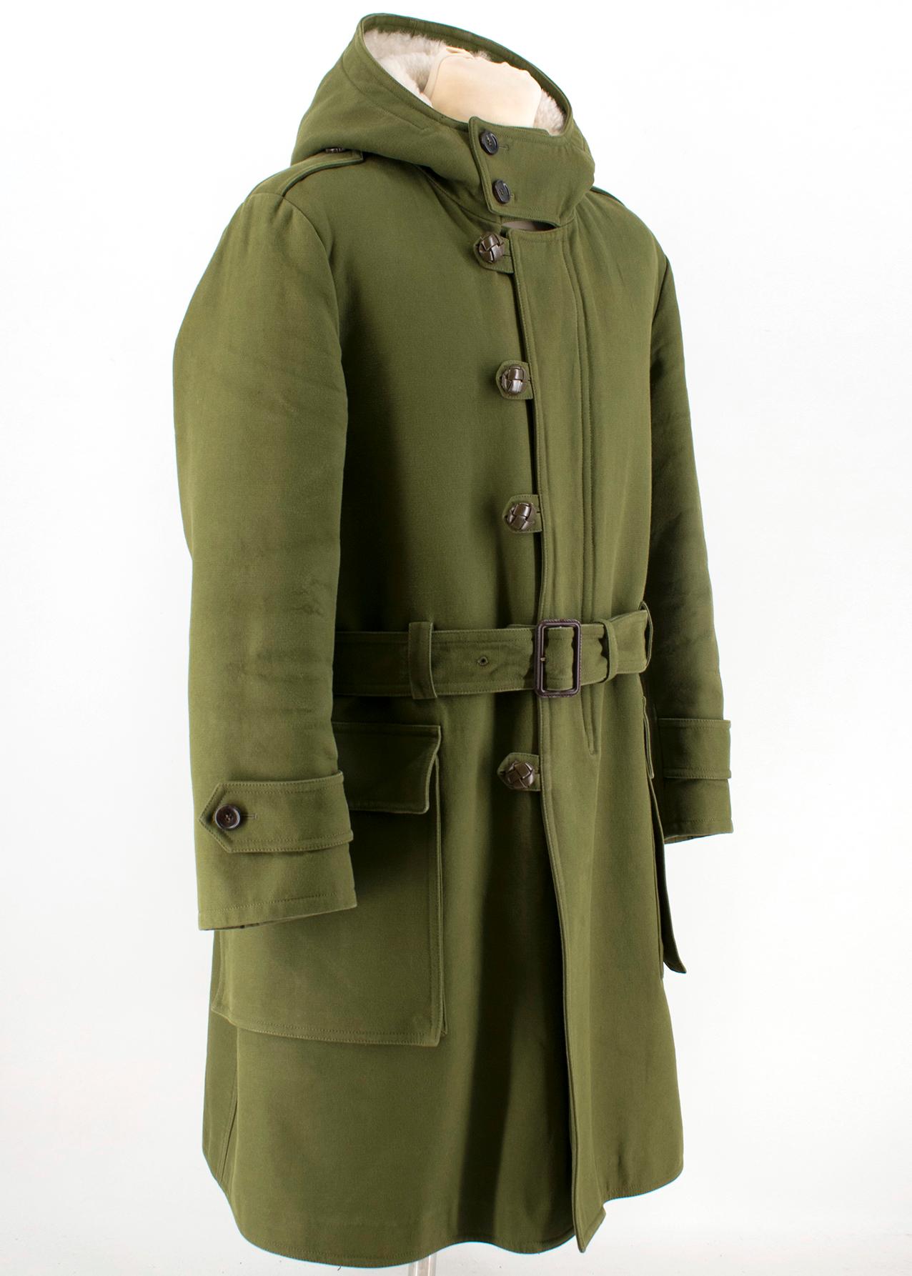 Gucci Shearling-Lined Green Canvas Parka

- Heavyweight coat 
- Military green wool & cotton-blend cotton canvas. 
- Lined with shearling. 
- Fixed hood. 
- Zipper and button closure. 
- Woven leather buttons. 
- Self-belt with leather-covered