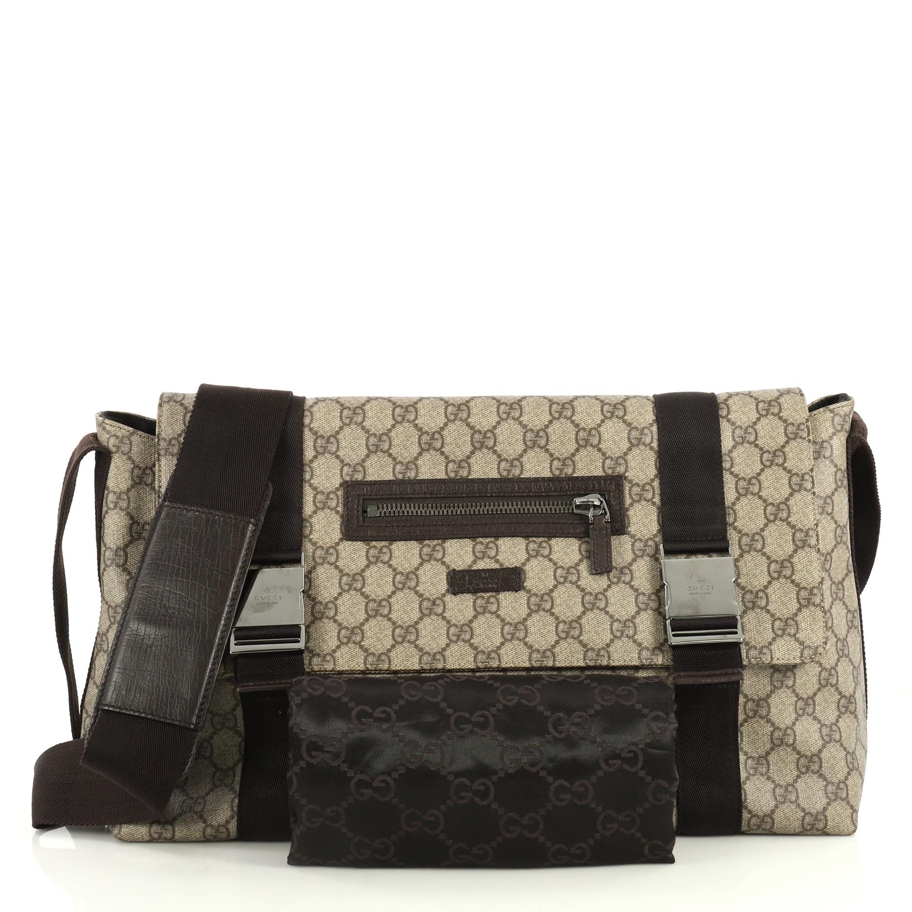 This Gucci Messenger Buckle Bag GG Coated Canvas Large, crafted from brown GG coated canvas, features adjustable shoulder strap, zip pocket on the front flap, and gold-tone hardware. Its buckle closure opens to a black fabric interior. 

Estimated