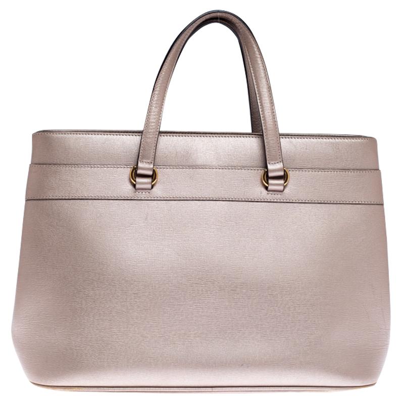 The classic Bright Bit handbag from Gucci is an example of the brand's exquisite craftsmanship. It is made from metallic beige leather and lined with canvas. It features two top handles and comes with a long detachable strap for convenience. It is