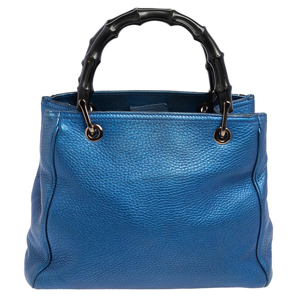 Designed with Gucci’s signature Bamboo top handles, this Shopper tote is instantly recognizable among fashion brand lovers. This elegant style is finely created from blue leather and is finished with an embossed Gucci trademark on the front. The