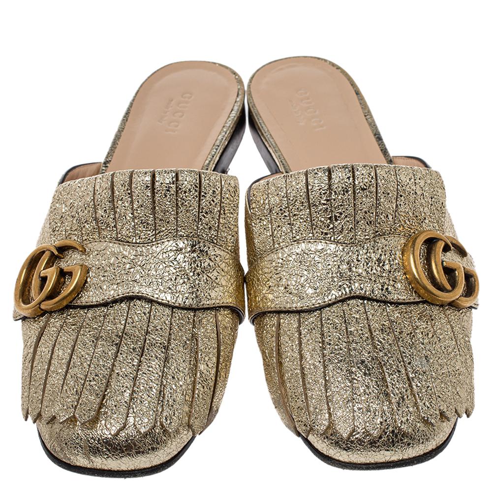 On-trend and easy to flaunt, this pair of Kiltie mules by Gucci is stunning. They've been crafted from metallic gold crackle leather and styled with folded fringes and the brand's signature GG in gold-tone on the uppers. Comfortable insoles complete