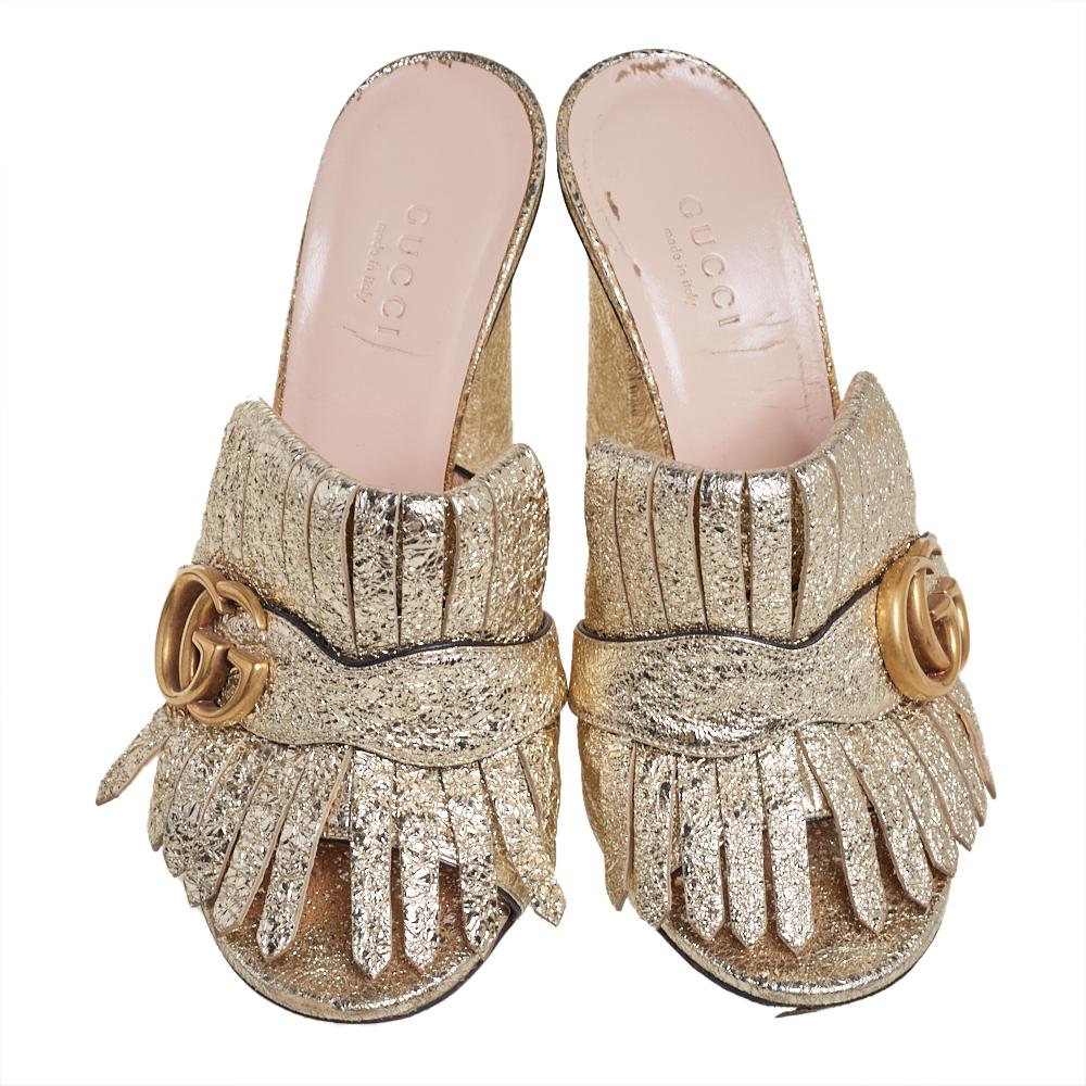 This pair of sandals by Gucci is a buy to wear and treasure. They've been crafted using metallic gold foil leather and styled with folded fringes and the brand's signature GG on the uppers. Open toes and a set of block heels complete the pair.

