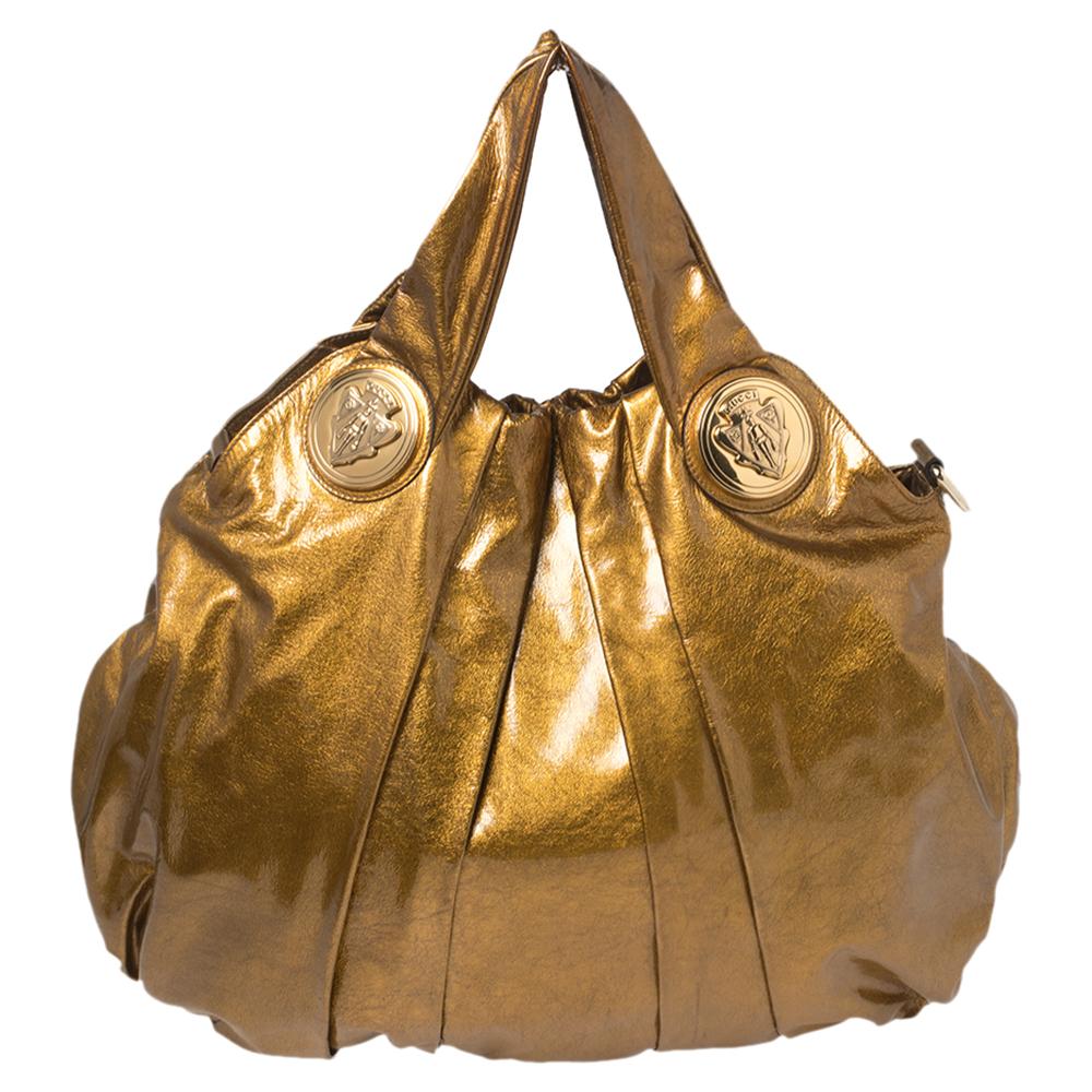 This Gucci hobo is built for everyday use. Crafted from leather, it has a glossy metallic gold exterior and two handles for you to easily parade it. The nylon and leather insides are sized well and the hobo is complete with the signature